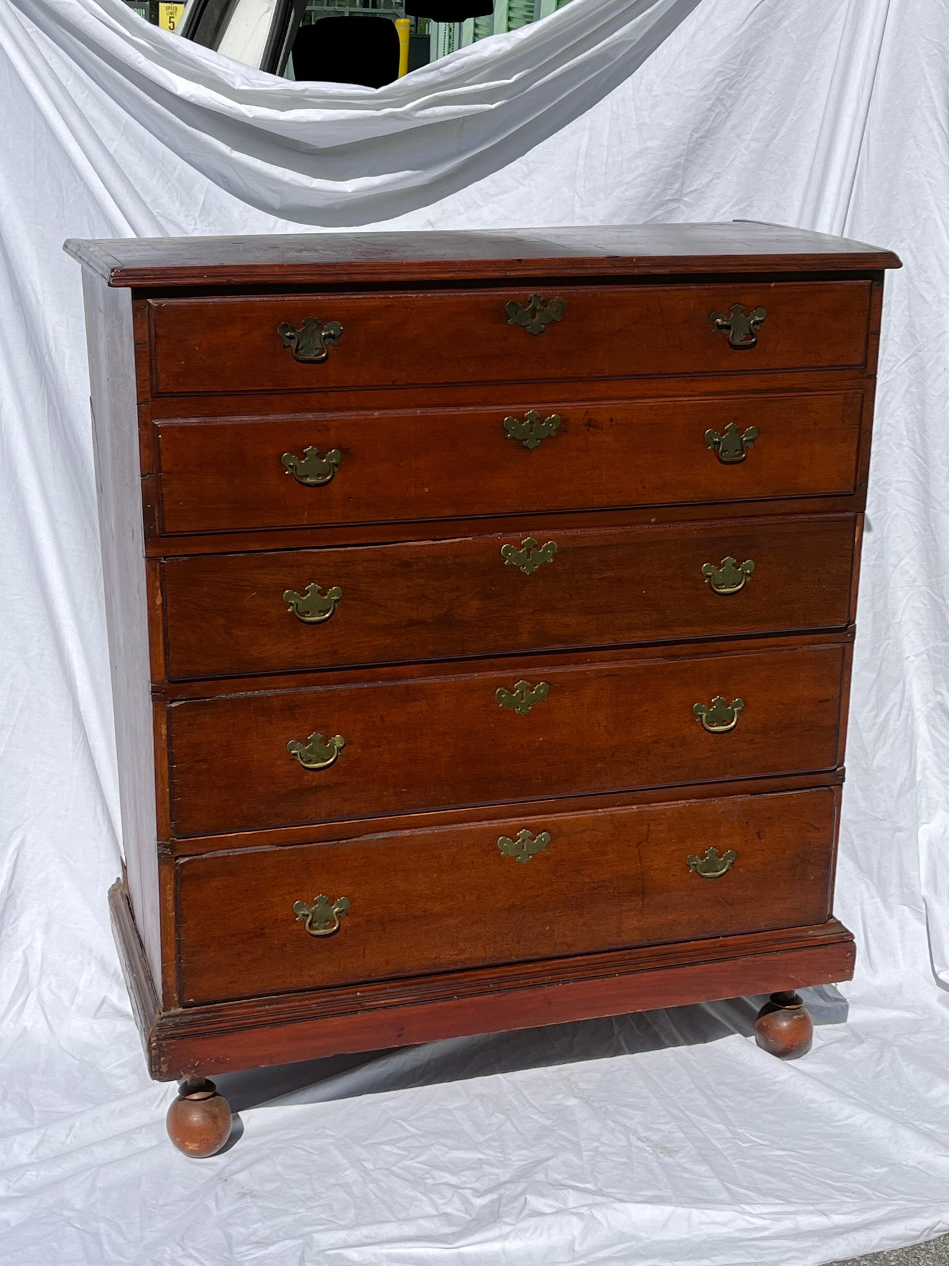 An antique mid to late 19th century William and Mary style Mule Chest with a hinged lid that opens to a blanket chest storage area with two false drawer fronts at the top. Underneath, there are three graduated drawers. Brass escutcheons and pulls. A