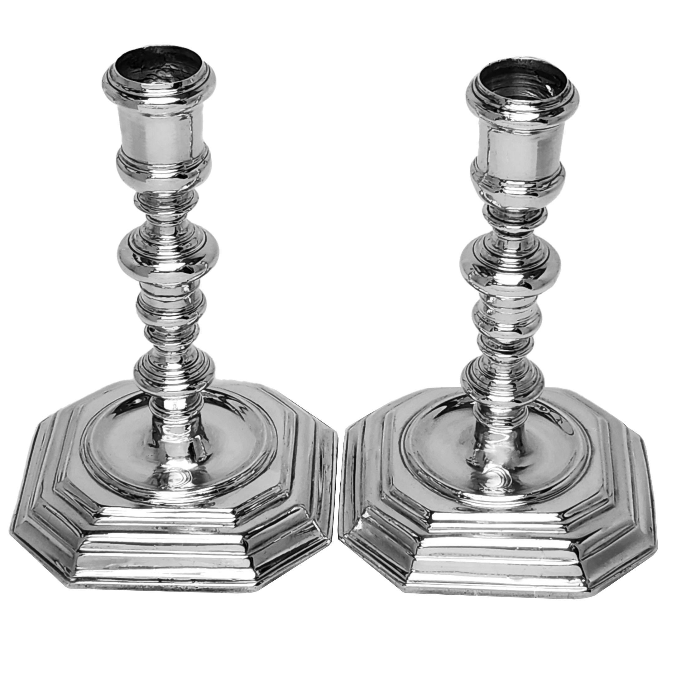 Un'eccellente coppia di candelieri in argento fuso William II. Questi candelabri d'argento del XVII secolo hanno una base quadrata con angoli tagliati a gradini, pozzi incassati e colonne bugnate. Ogni candeliere ha un piccolo stemma inciso