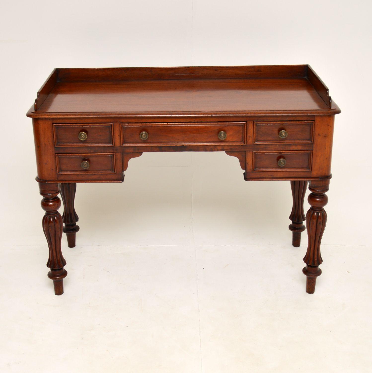 A gorgeous antique William IV period writing table in solid mahogany. This dates from circa 1830s-1840s.

It is of extremely high quality, with thick turned and fluted legs, original brass handles and a gallery around the top. The mahogany has a