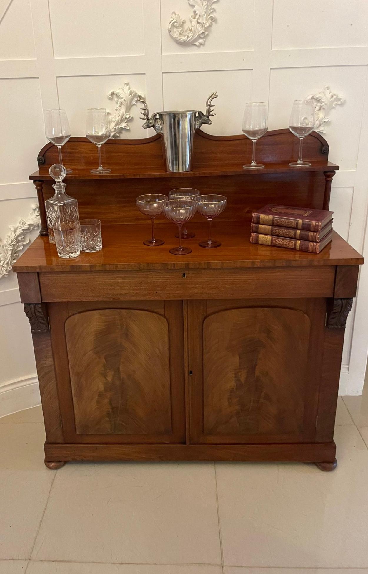 Antico chiffoniere in mogano di qualità William IV con piano sagomato intagliato sopra una mensola in mogano sostenuta da colonne tornite, piano in mogano figurato sopra un lungo cassetto, mensole intagliate di qualità, coppia di porte pannellate in
