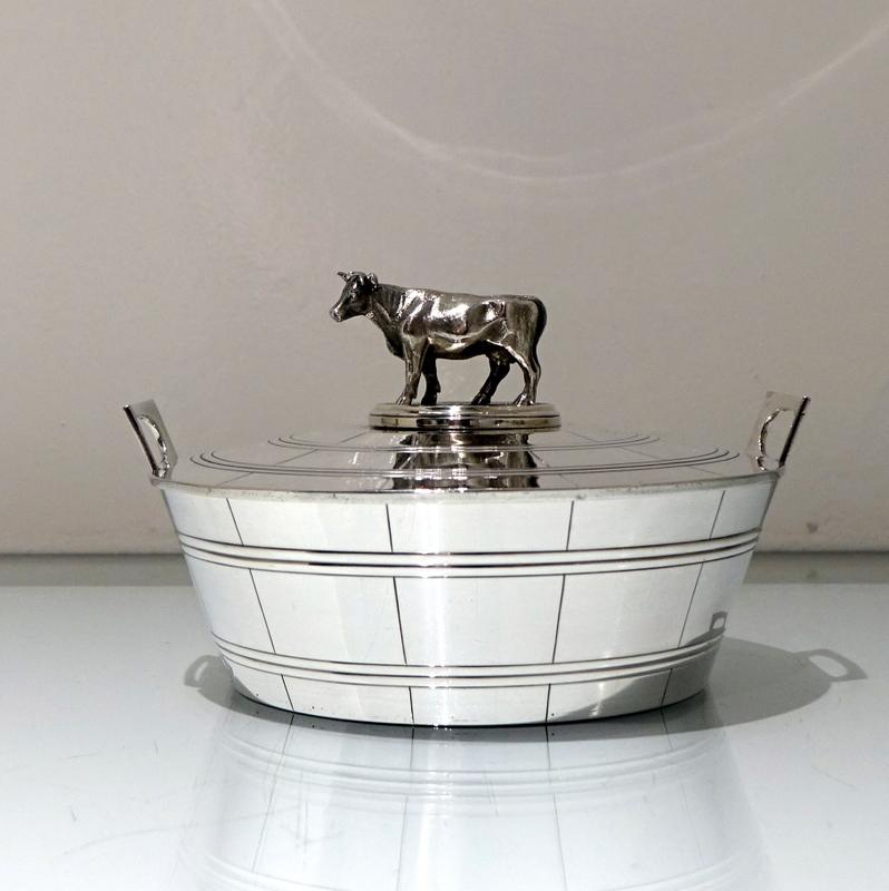 A very stylish butter dish designed by the highly renowned Charles T Fox. The body of the dish is modelled in the form of a milk pail and has elegant floating handles in which sits a push fit detachable lid. The lid is then mounted by a stunning