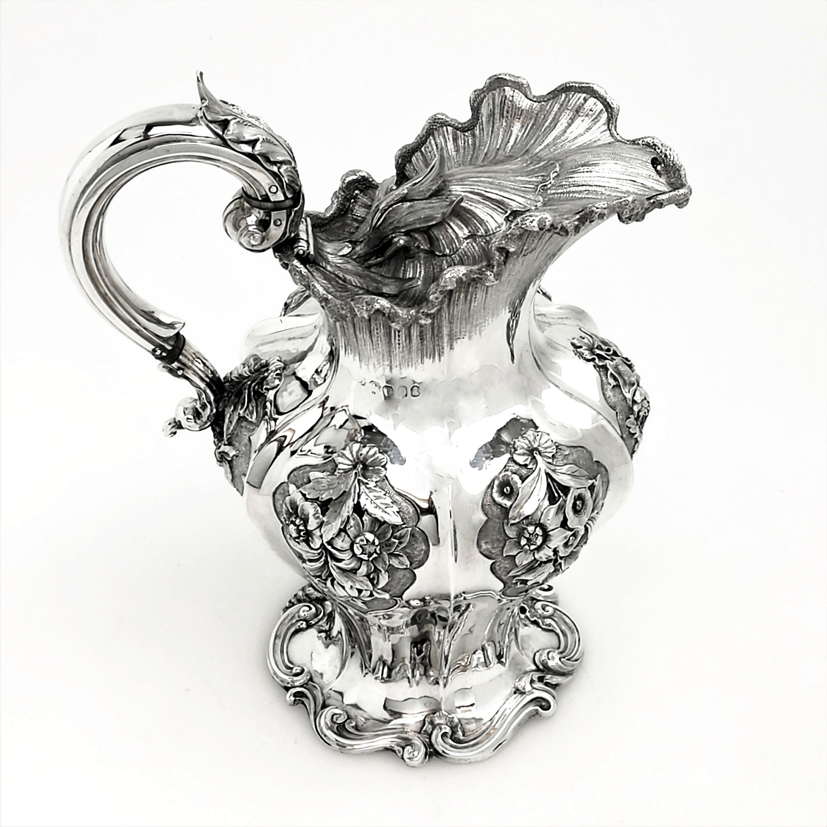 A magnificent antique William IV solid Silver Jug with an elegant shaped body. The Jug is embellished with beautiful shaped cartouches on each panel filled with chased flowers. The rim and spout of the Jug are shaped and textured, and the lid is