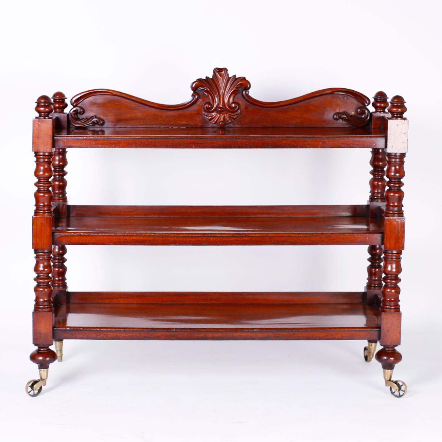 A superb English étagère, server or set of shelves, crafted in the 19th century in the William IV style, with mahogany featuring a serpentine back splash with center carving, three shelves supported by turned supports over turned onion feet on the