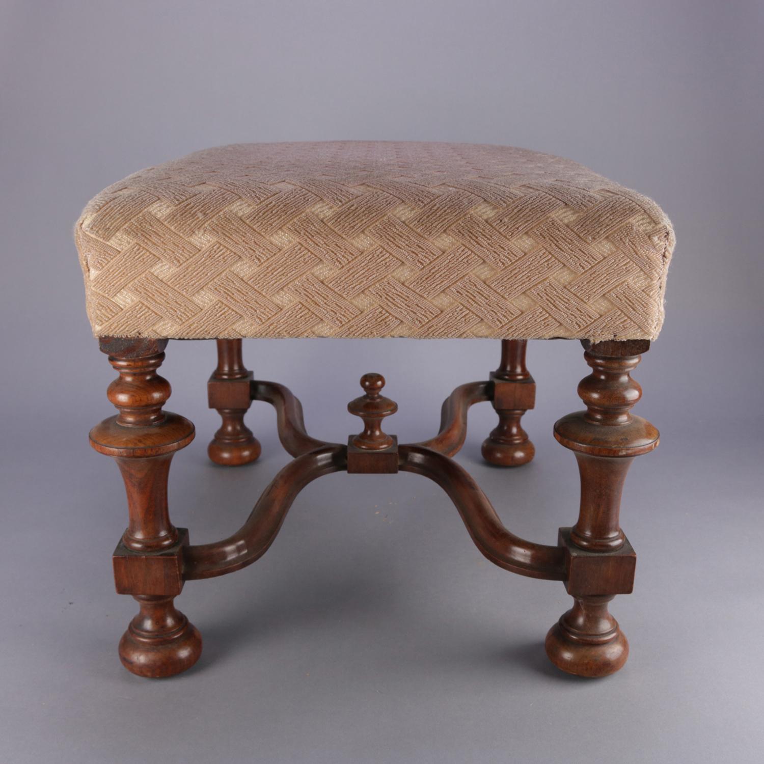An antique William and Mary style footstool features carved walnut frame with turned legs and x-form stretcher having central final, upholstered seat, circa 1930.

Measures: 16