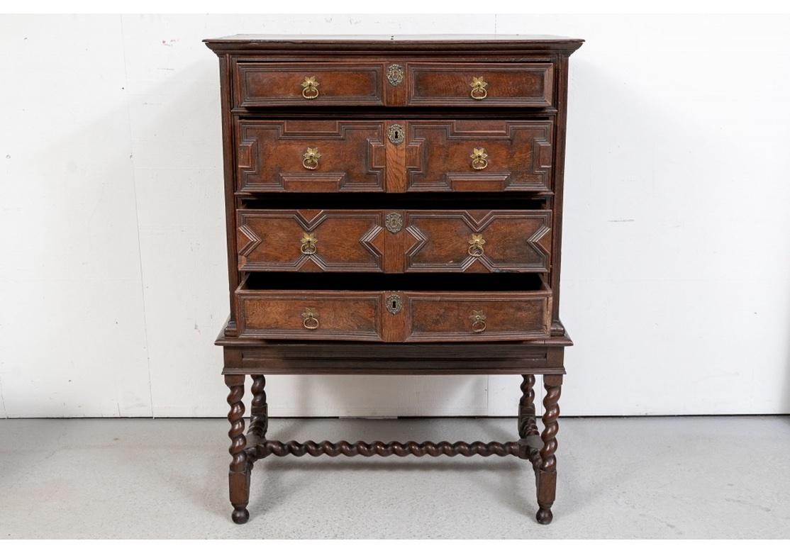 Finely carved dark wood chest with four long graduated drawers with carved moldings, brass escutcheons (lacking a key) and fine twin flower form ring pulls to each drawer. The stand with barley twist legs and center stretcher on block shaped and