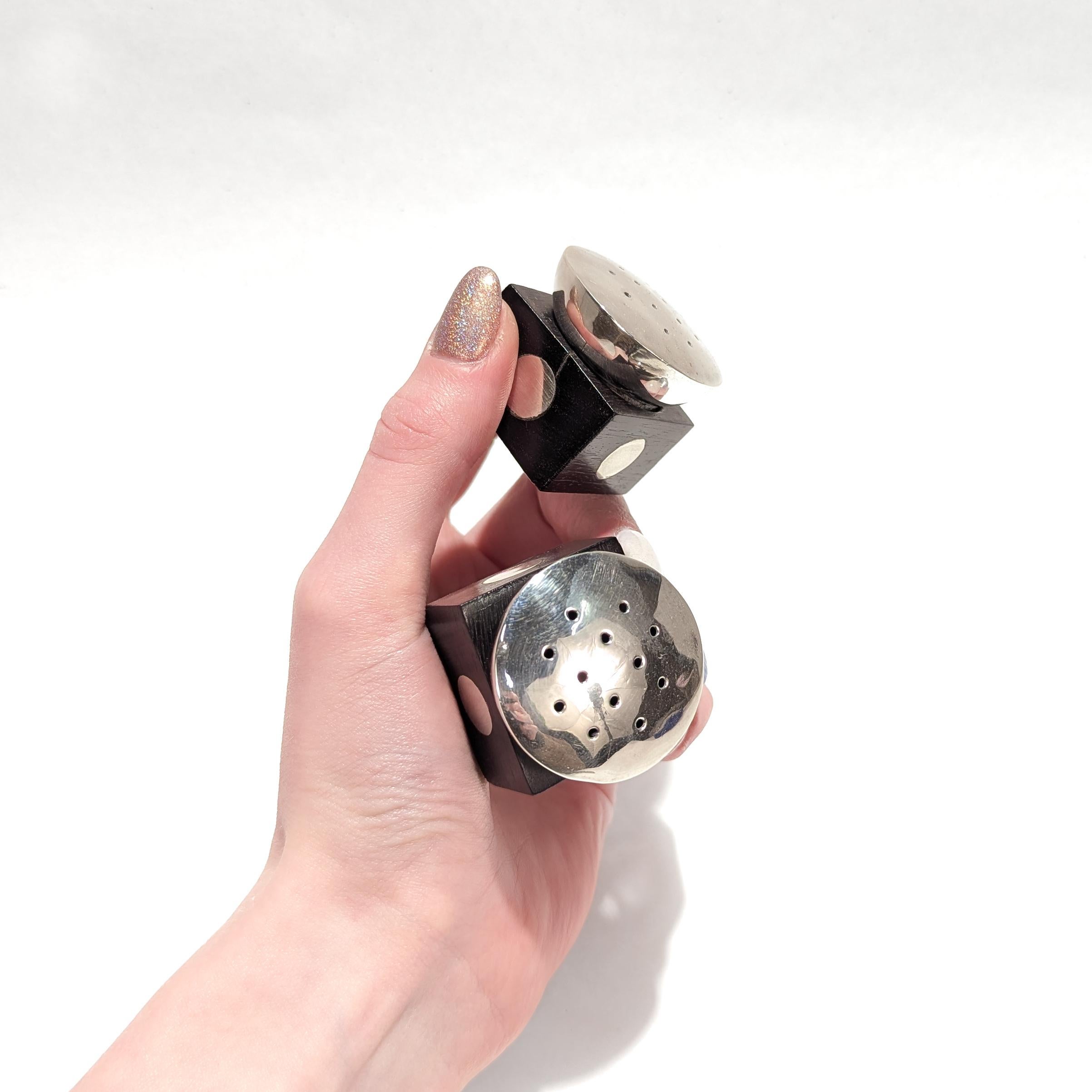 A fine pair of silver & ebony wood salt & pepper shakers.

In sterling silver.

By William Spratling of Taxco, Mexico.

Each with a square ebony block with silver accents supporting a large silver shaker head.

Marked to the base of each with