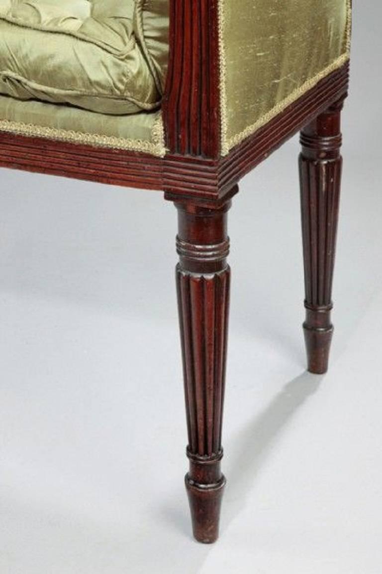 A late George III mahogany window seat on finely turned reeded legs.