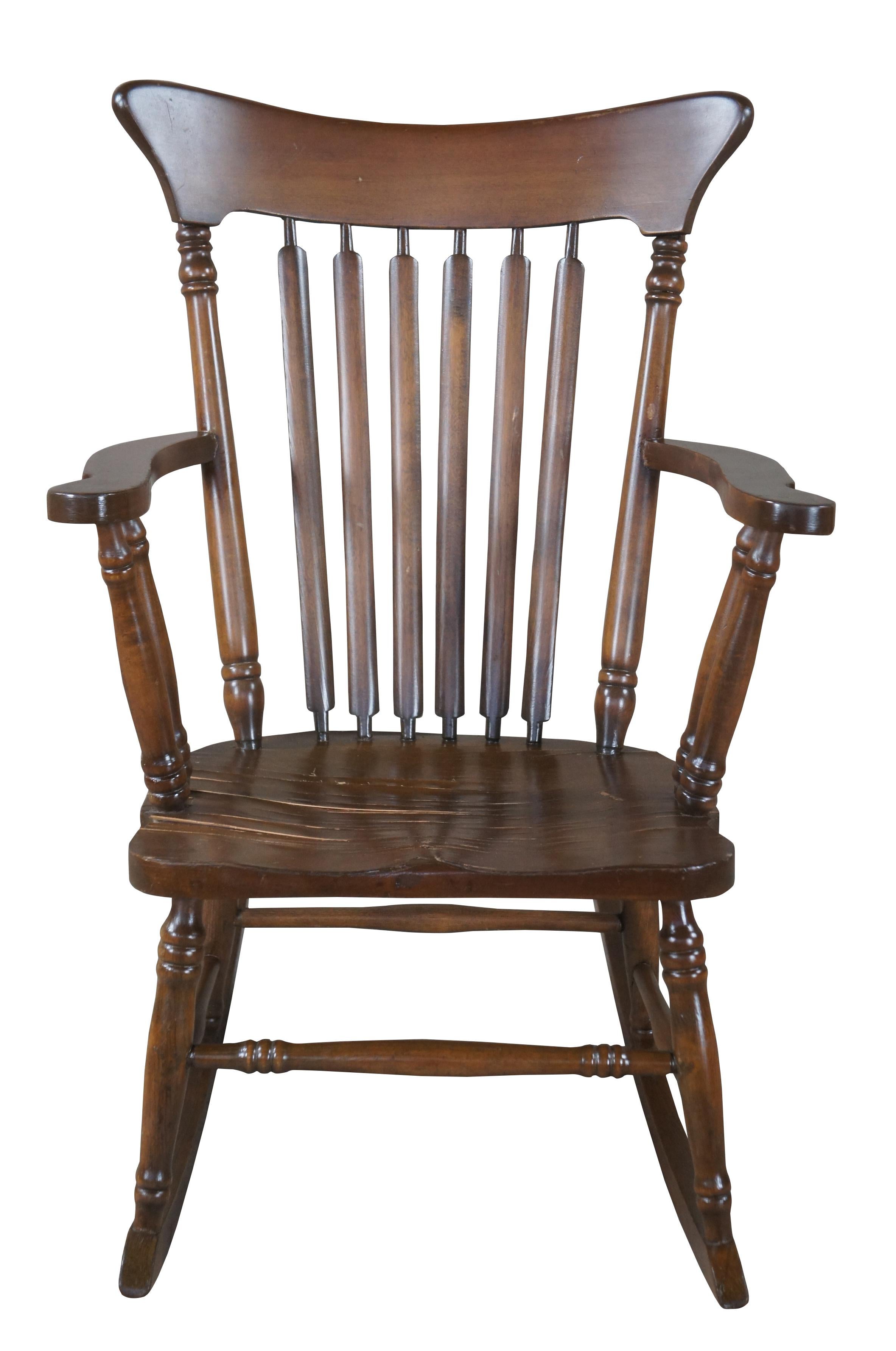 A lovely rocking chair from the first half of the 20th century.  Made from maple with a combination of Windsor and farmhouse styling.  Features a contoured crest rail, slat back and saddle seat.  Features turned arm supports and stretchers. 