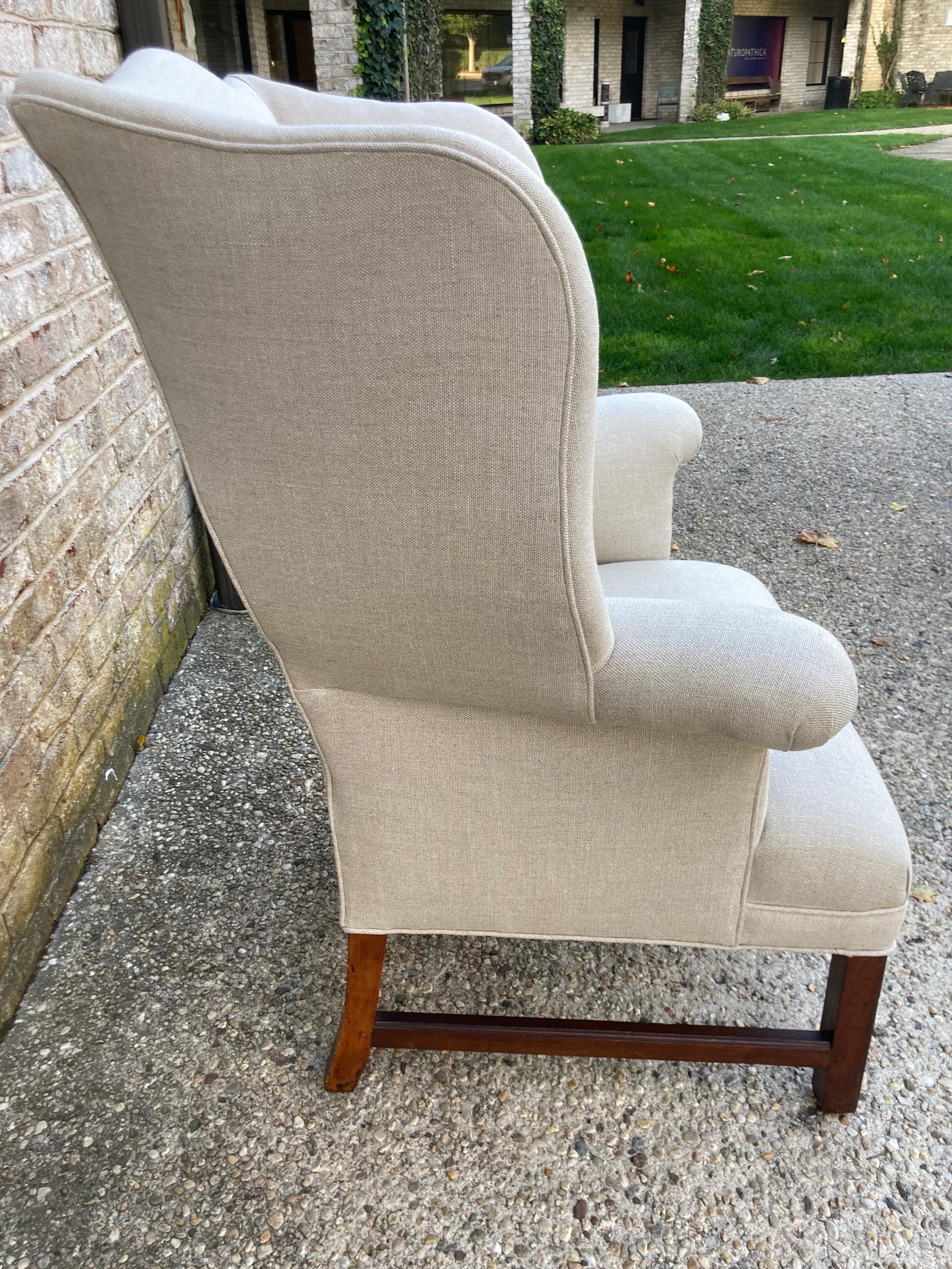 Great antique wingback chair with a tight seat. Newly reupholstered in natural linen. Chippendale style legs.