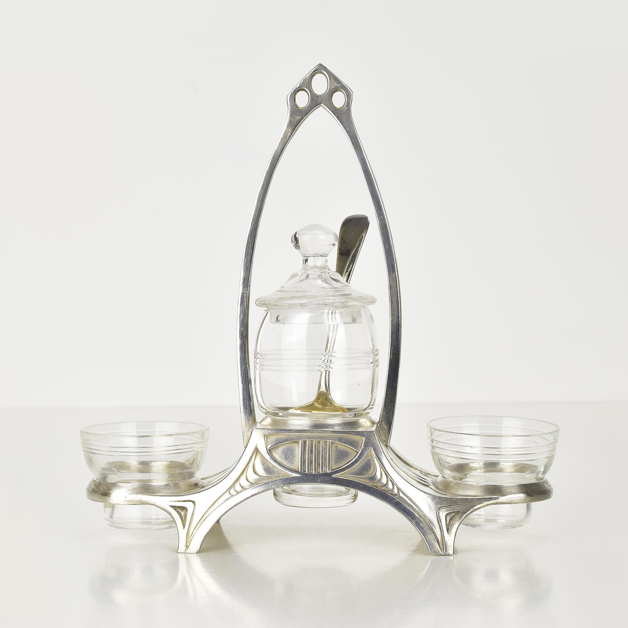 Cette exquise salière et épicière ancienne avec pot à moutarde centré est un magnifique exemple du design Art Nouveau du célèbre fabricant allemand WMF (Württembergische Metallwarenfabrik). Le cadre plaqué argent présente une forme gracieuse et
