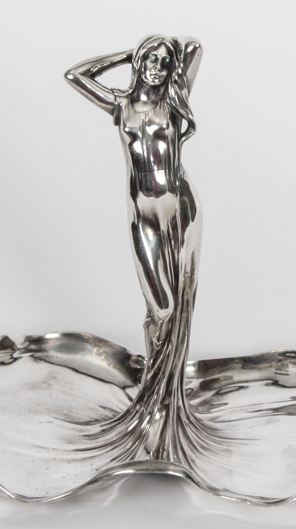 This is a beautiful WMF Art Nouveau silver plated visiting card tray Circa 1900 in date.

Depicting a female figure in a long, flowing diaphanous dress, the train forming the double sided tray, with the impressed maker's mark and stamped '169' to