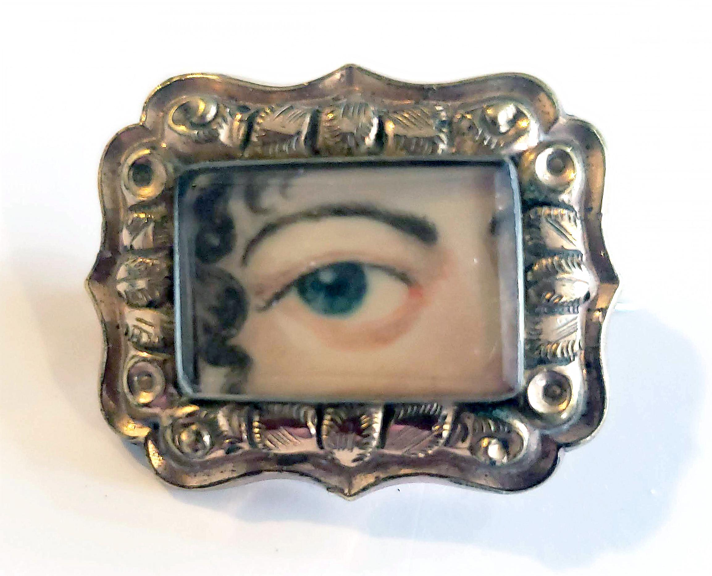 English Antique Lover's eye portrait miniature brooch.
circa 1840-50

The charming oval-shaped portrait miniature is mounted in a gilt metal repoussé frame with a pin back with a gilt leaf design on each side. The portrait is of a woman's right