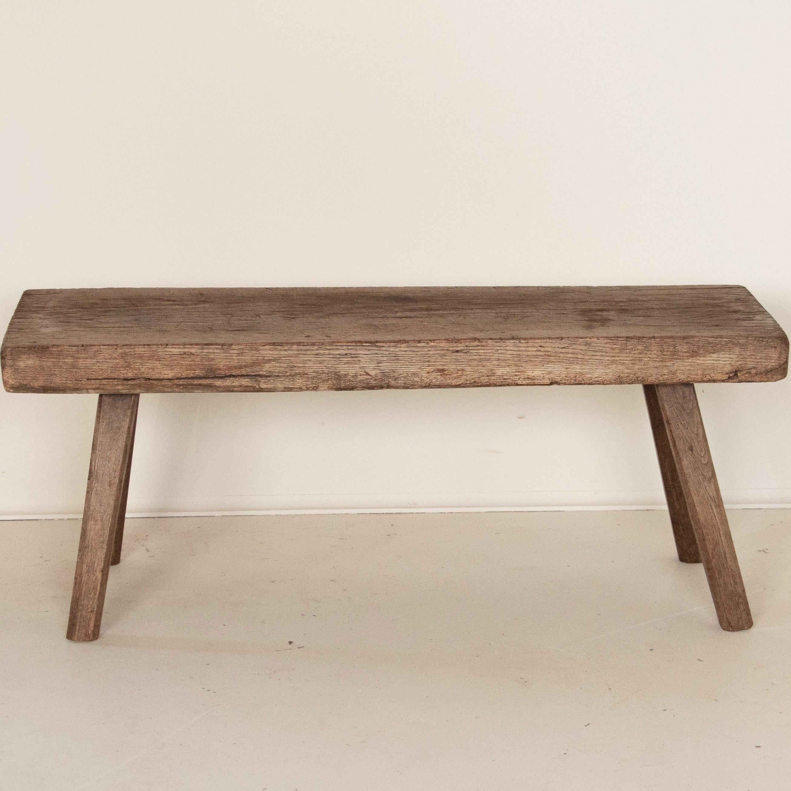 There is something organic and inviting in the thick wood top of this rustic peg leg bench. It is the years of use that have deepened its character, with a wonderful worn patina grown richer over time. While it was likely that it originally served