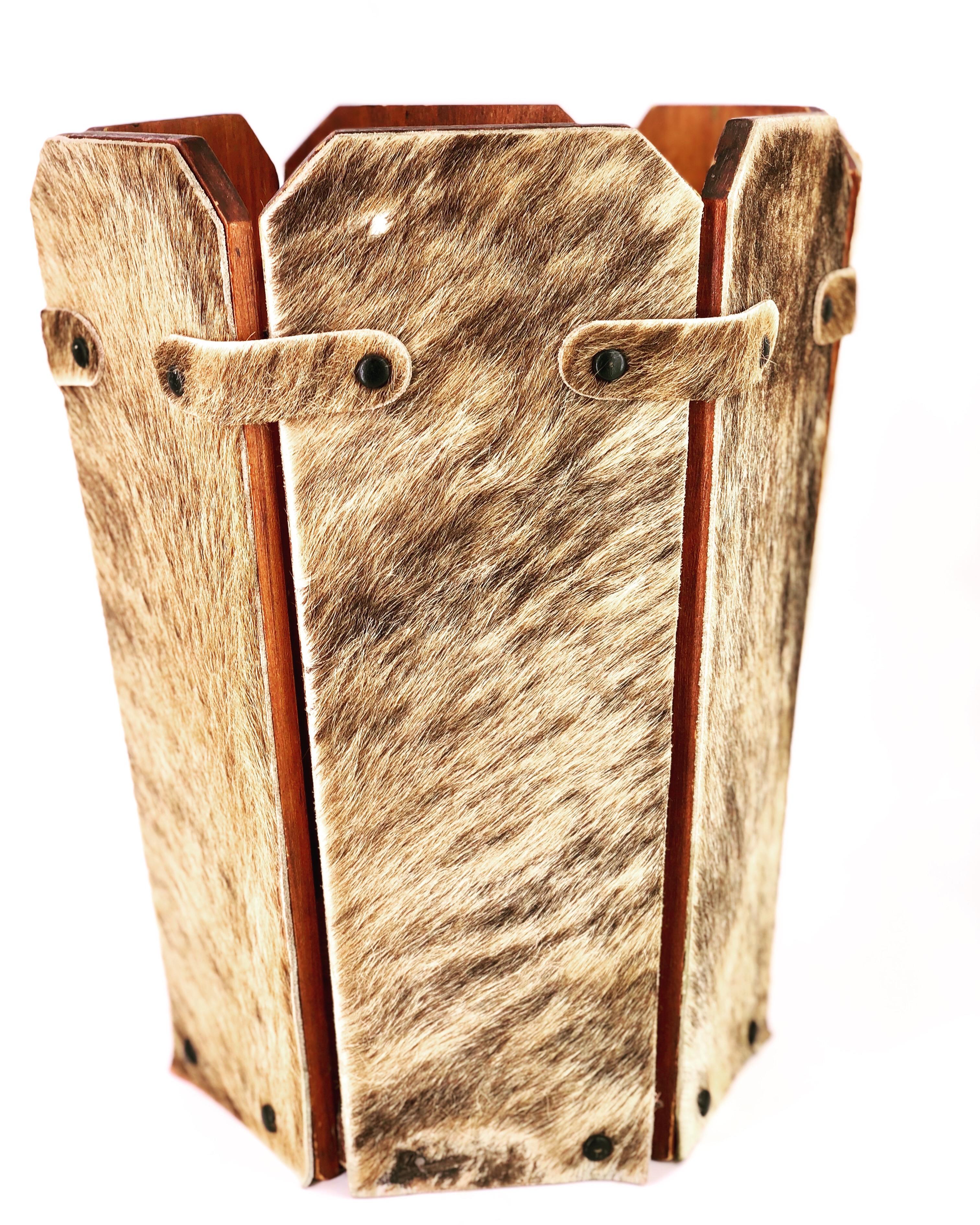 A very unique antique rustic cowhide covered wastebasket, circa 1950s, six planks of wood covered in cowhide, united with leather straps even the bottom it's covered with cowhide.
