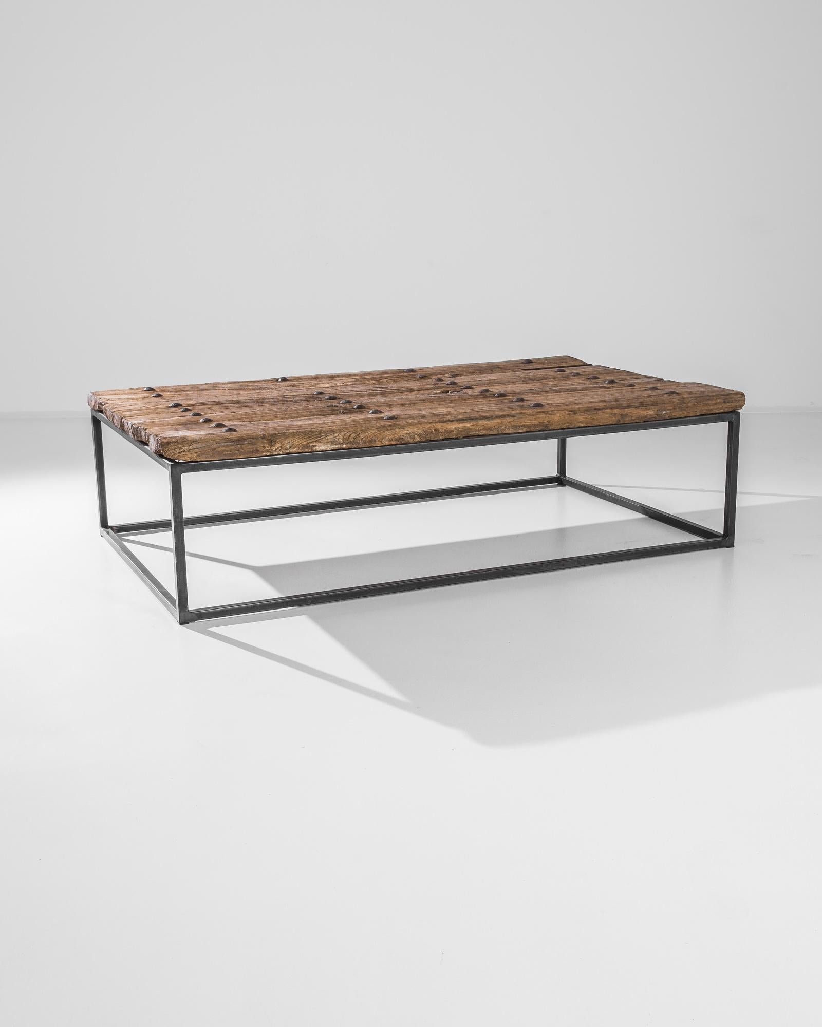 A wooden and metal door from China, circa 1900, rests on a steel base. Blending sleek and rustic, this 17.7” tall coffee table makes a comfortable and stylish place to rest your drink. A simple symmetry sings in this handcrafted table featuring a
