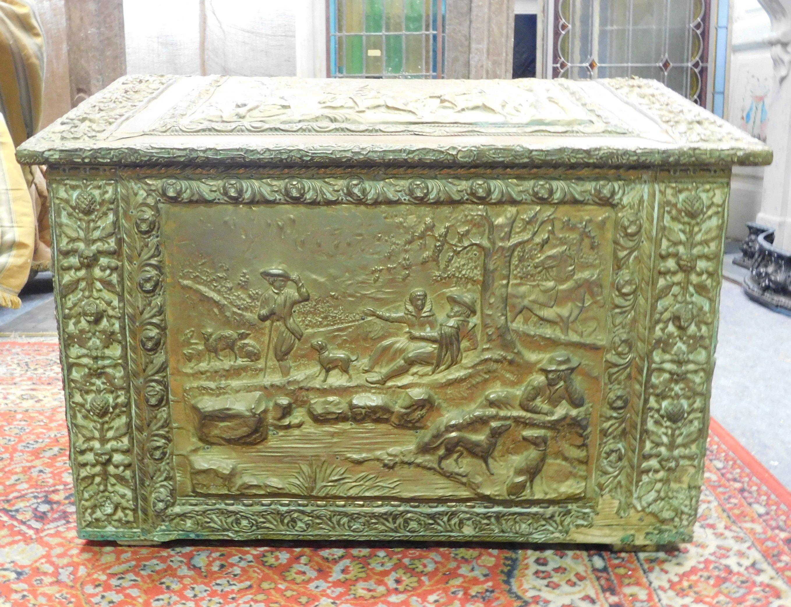 Antique wood-holder covered in embossed brass, wood covered with embossed and sculpted sheet metal, then gilded, with scenes of everyday life of the time. Built by hand in the late 19th century, it can be used as a storage box, log holder, chest,