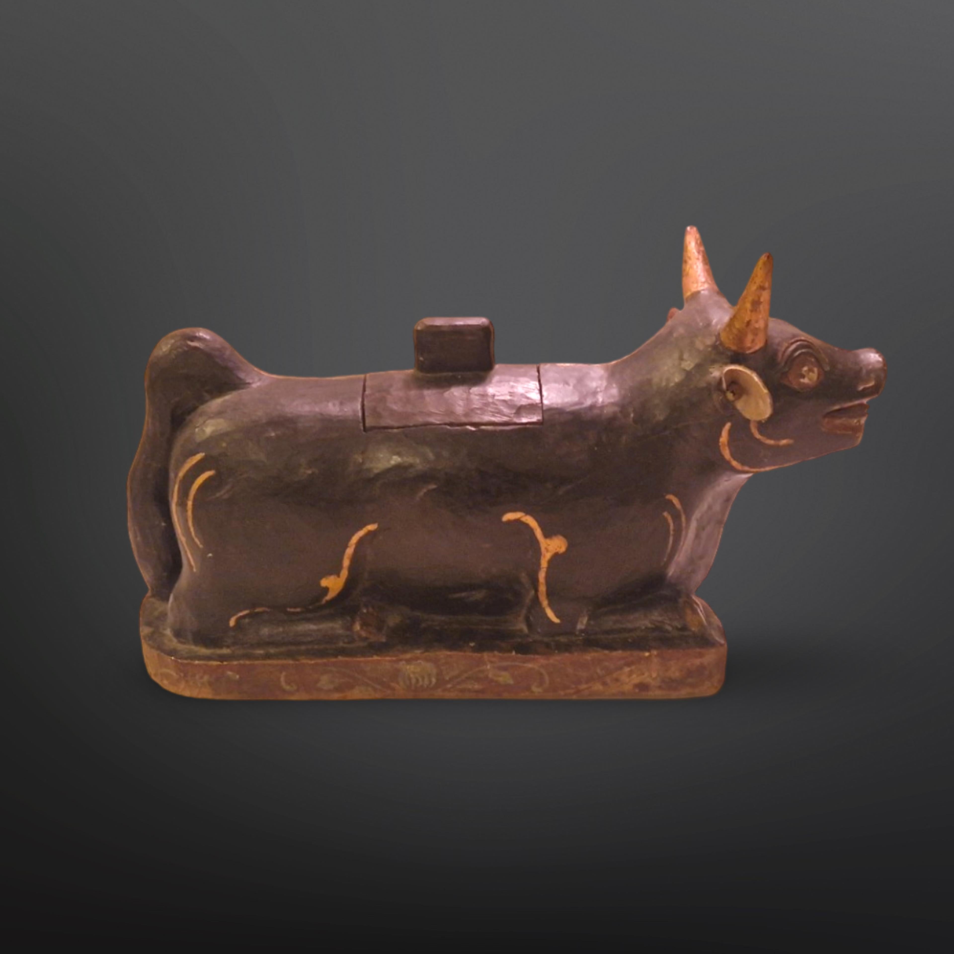 Hand carved and hand painted wood Nandi bull statue. Made around the turn of the 20th century in India. It depicts Vahana, the bull of hindu god Shiva. The statue has a small compartment with a lid on its back. This was probably meant to store an