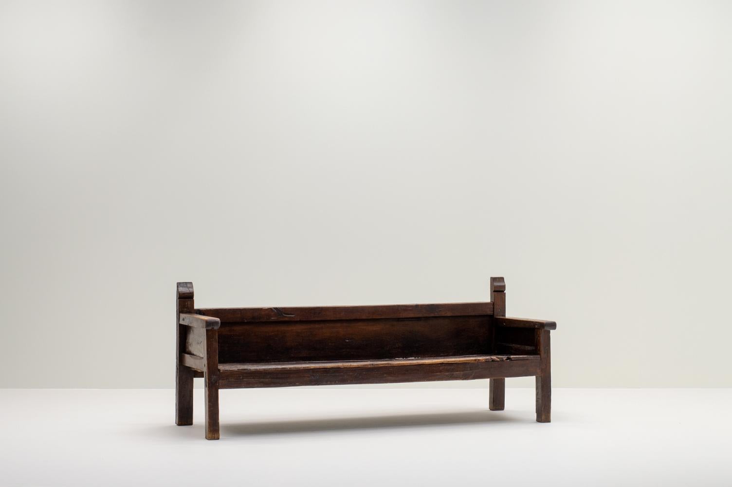 Antique wooden bench, 19th century Spain. Minimalistic handmade bench from the 19th century. The bench has a low back and a deep seat. The color is a dark brown stain and has a beautiful patina. Structurally in good condition. 

.