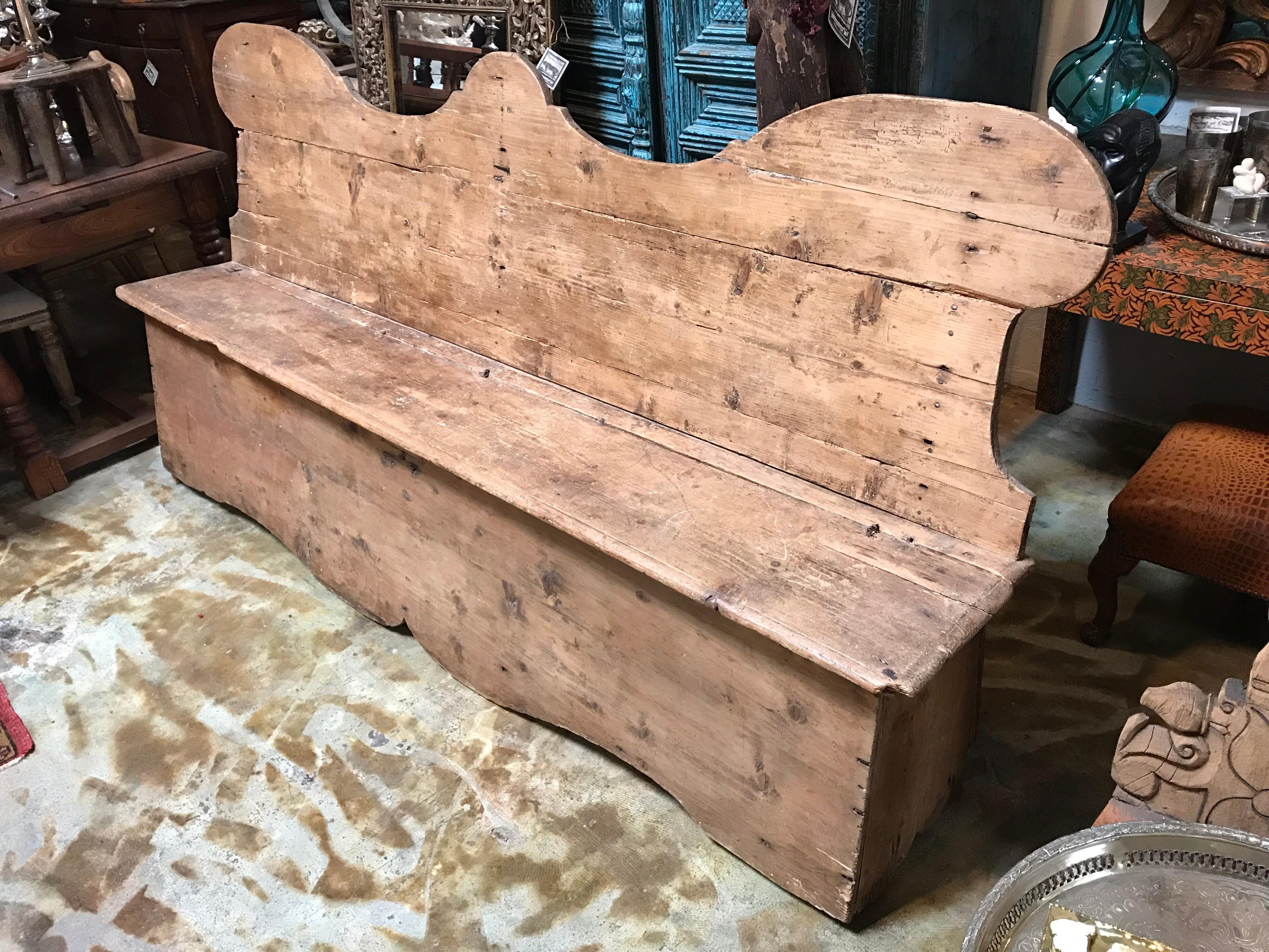 Banc en bois. Fabriqué au 18e siècle. Le siège s'ouvre sur une charnière pour le rangement.