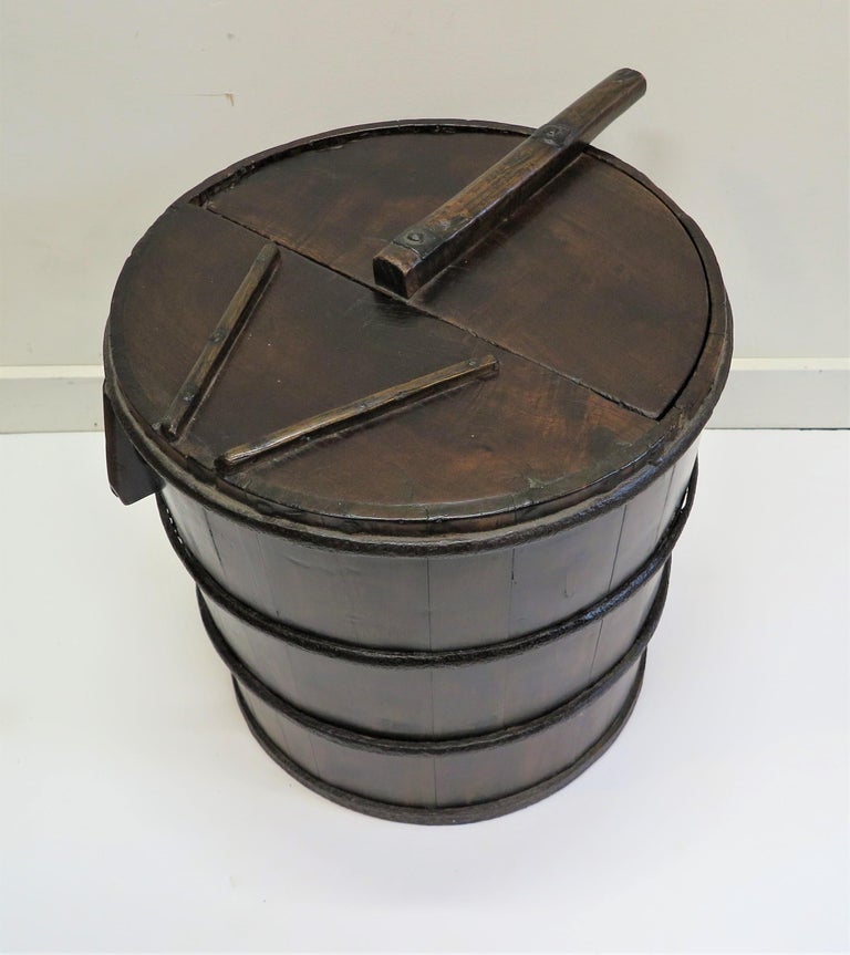 Antique wooden milk farm bucket. Wooden bucket pail having heavy hand forged iron banding. Two solid wooden handles specifically for titling the bucket to pour liquid. The top is divided into two semi circles one attached top has a funnel like