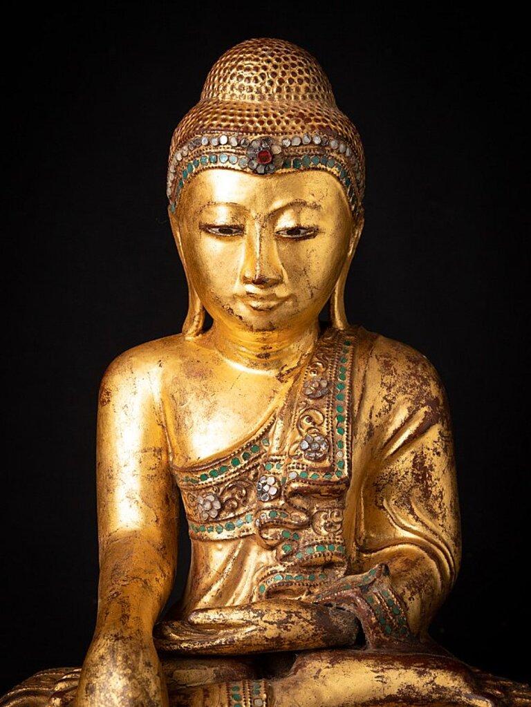 Material: wood
43 cm high 
35,3 cm wide and 24,3 cm deep
Weight: 6.013 kgs
Gilded with 24 krt. gold
Mandalay style
Bhumisparsha mudra
Originating from Burma
19th century
With inlayed eyes.
 