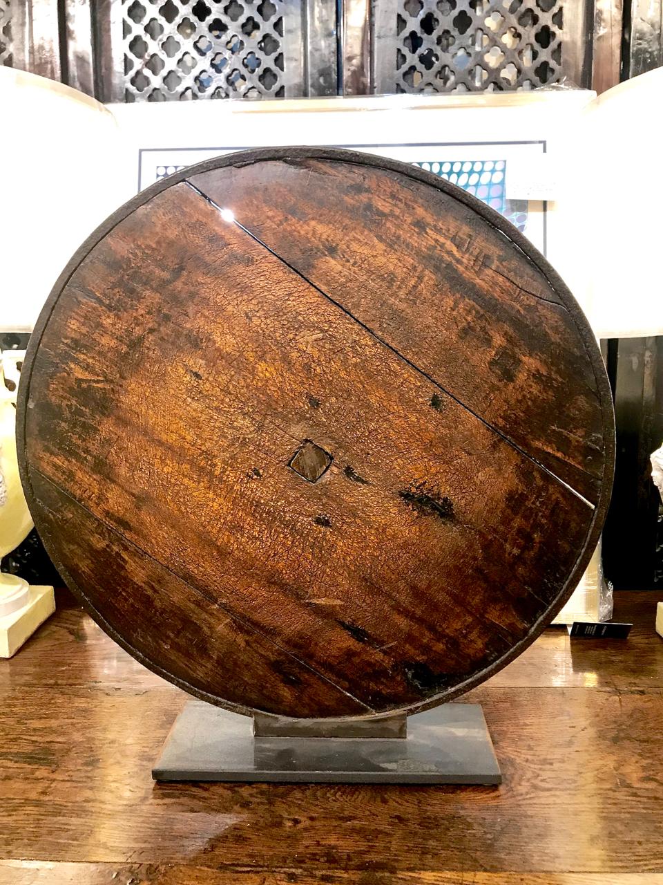This is a beautifully patinated 18th or 19th century cart wheel. The wooden wheel retains is original hand forged iron rim and its forged iron reinforcements. The circular form symbolizes wholeness and oneness. The wheel is displayed on a custom