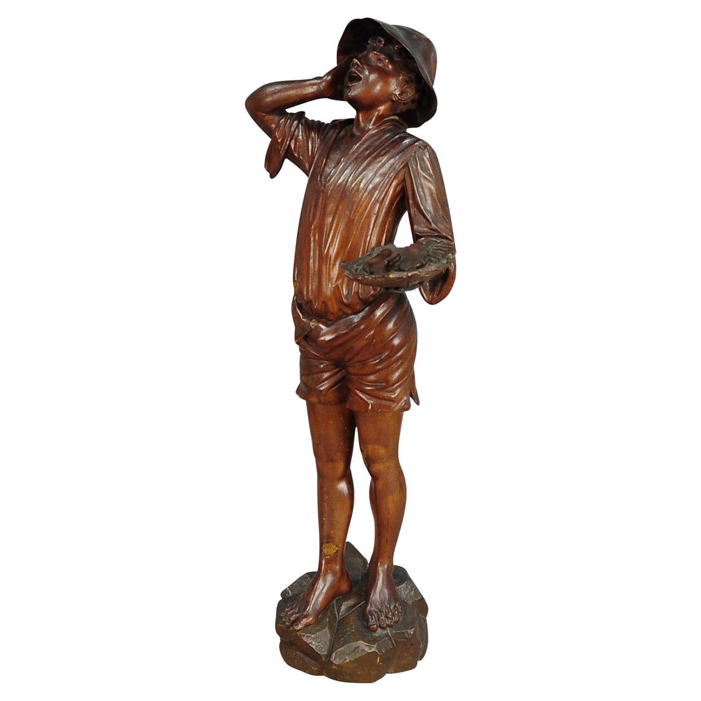 Statue ancienne en bois sculpté d'un jeune pêcheur