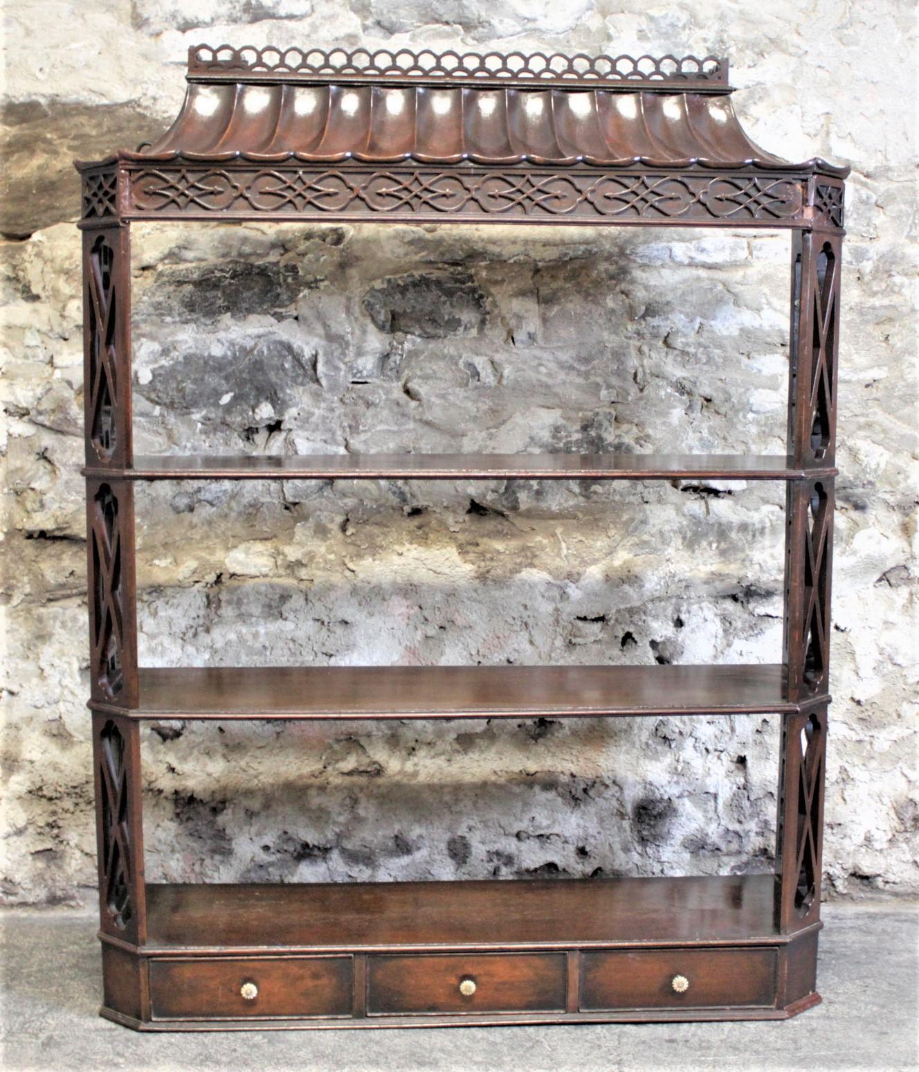 This elaborate antique hanging wall shelf has no indication of its maker, but it is presumed to have been made in England in circa 1790 in the period Chinese Chippendale style. This shelf as a very contoured pagoda styled top which has nice and