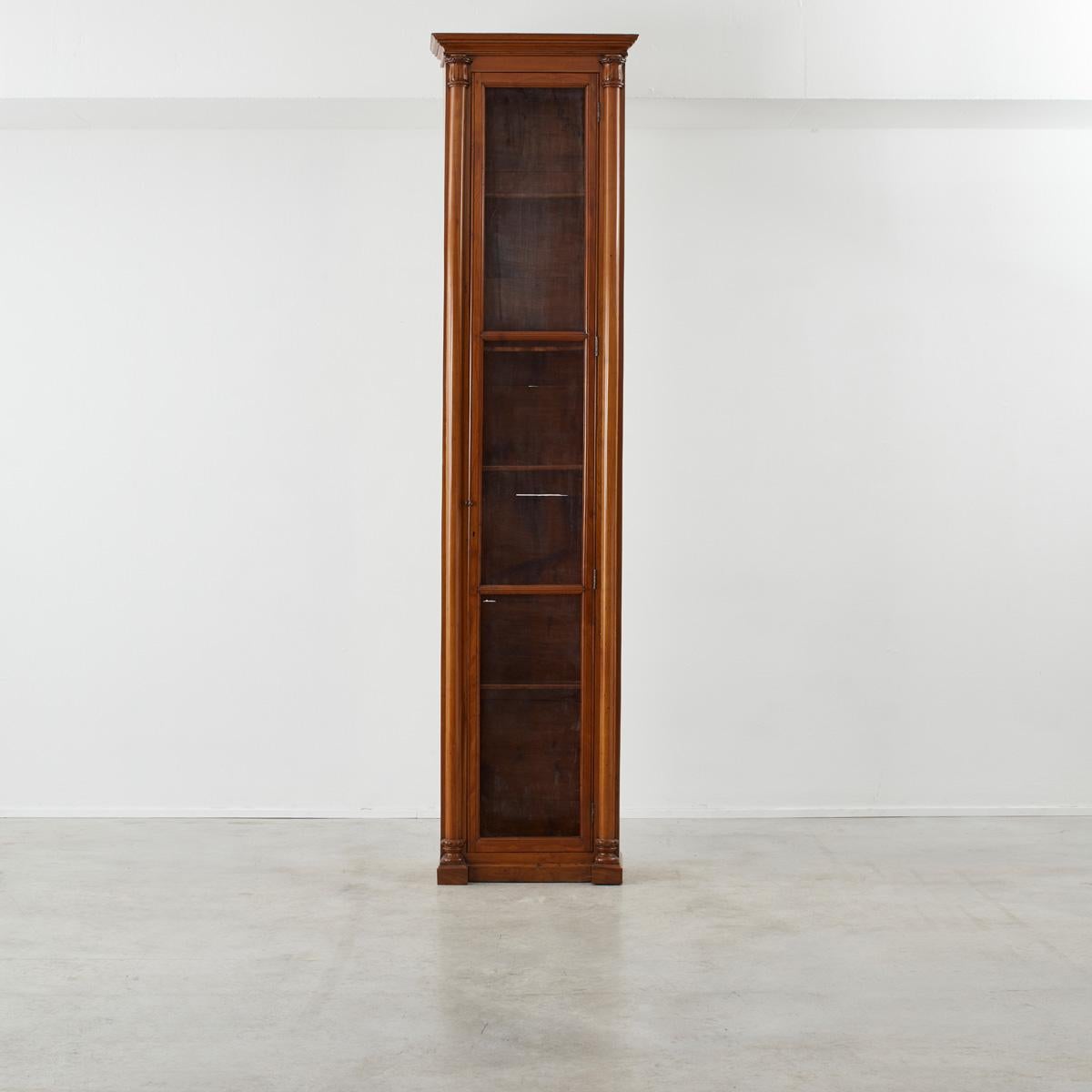A monumental  towering wooden column bookcase, thought to have been designed for offices of importance in 19th century England. Interchangeable slats allow for the heights of the shelves to be customised to the users need, with a mesh lined door