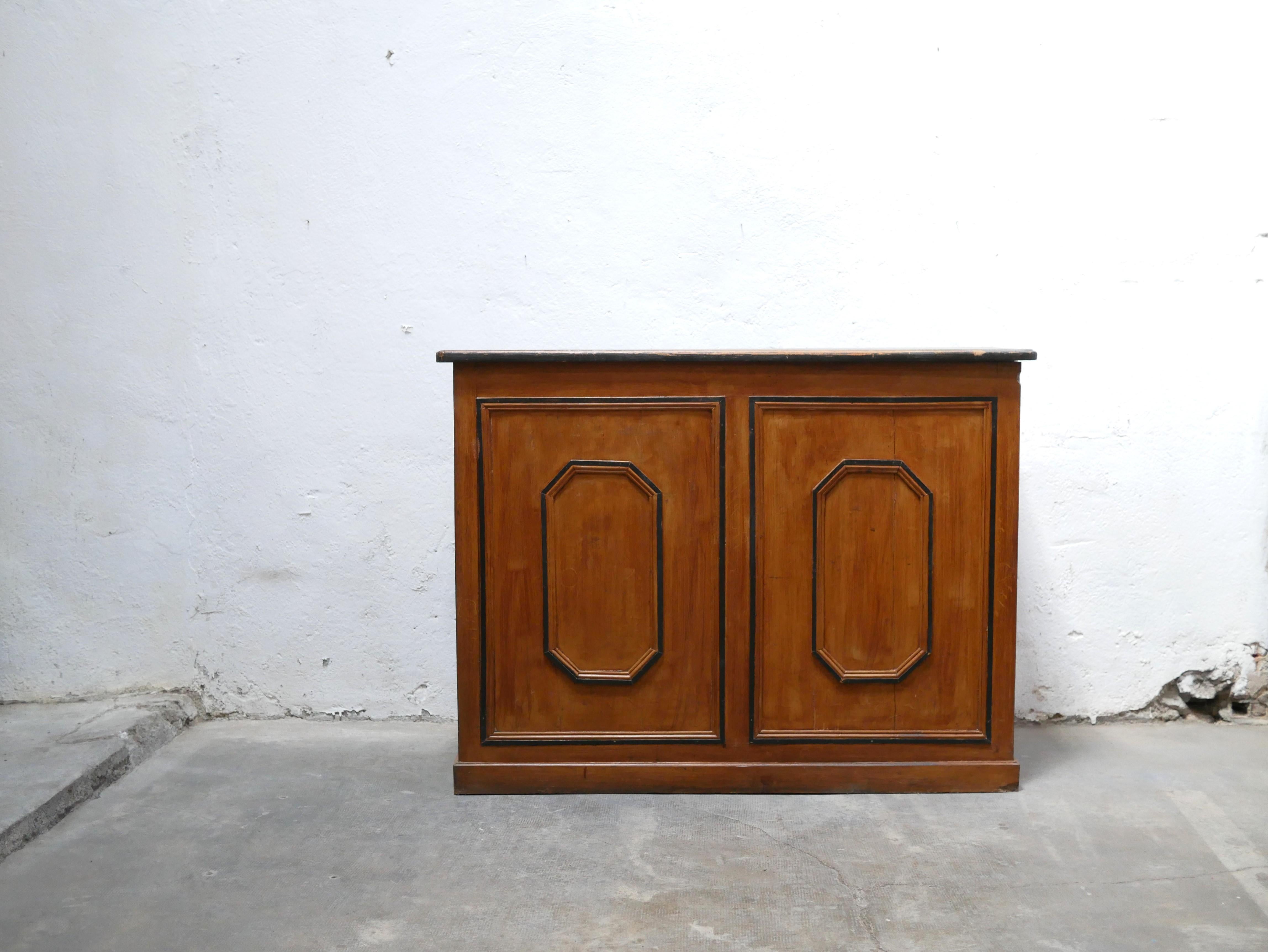 Wooden counter dating from the 1940s.

Authentic, practical and aesthetic, its pretty patina gives it a lot of character and elegance. Its top, which had been painted black, gives it a raw and modern side.
It will be perfect in a current decoration,