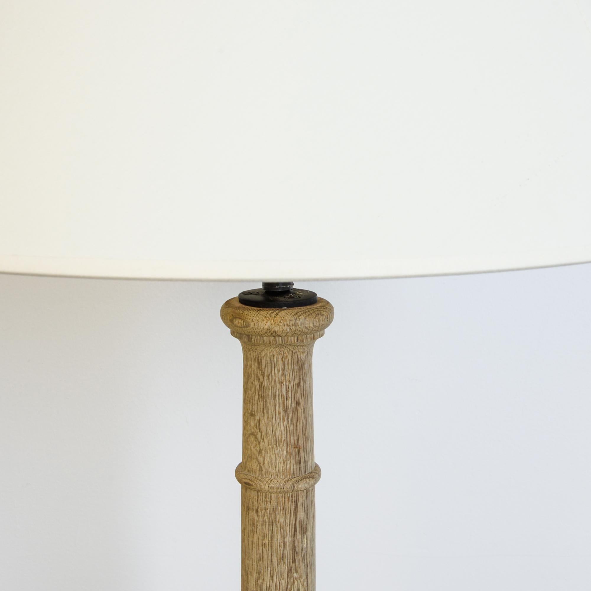 From France circa 1900, this lamp is constructed from an antique wooden plinth, updated with modern electrical wiring. With a classical influence, this elegant column is turned from cold- growth oak, a beautiful dense wood, and framed with a small