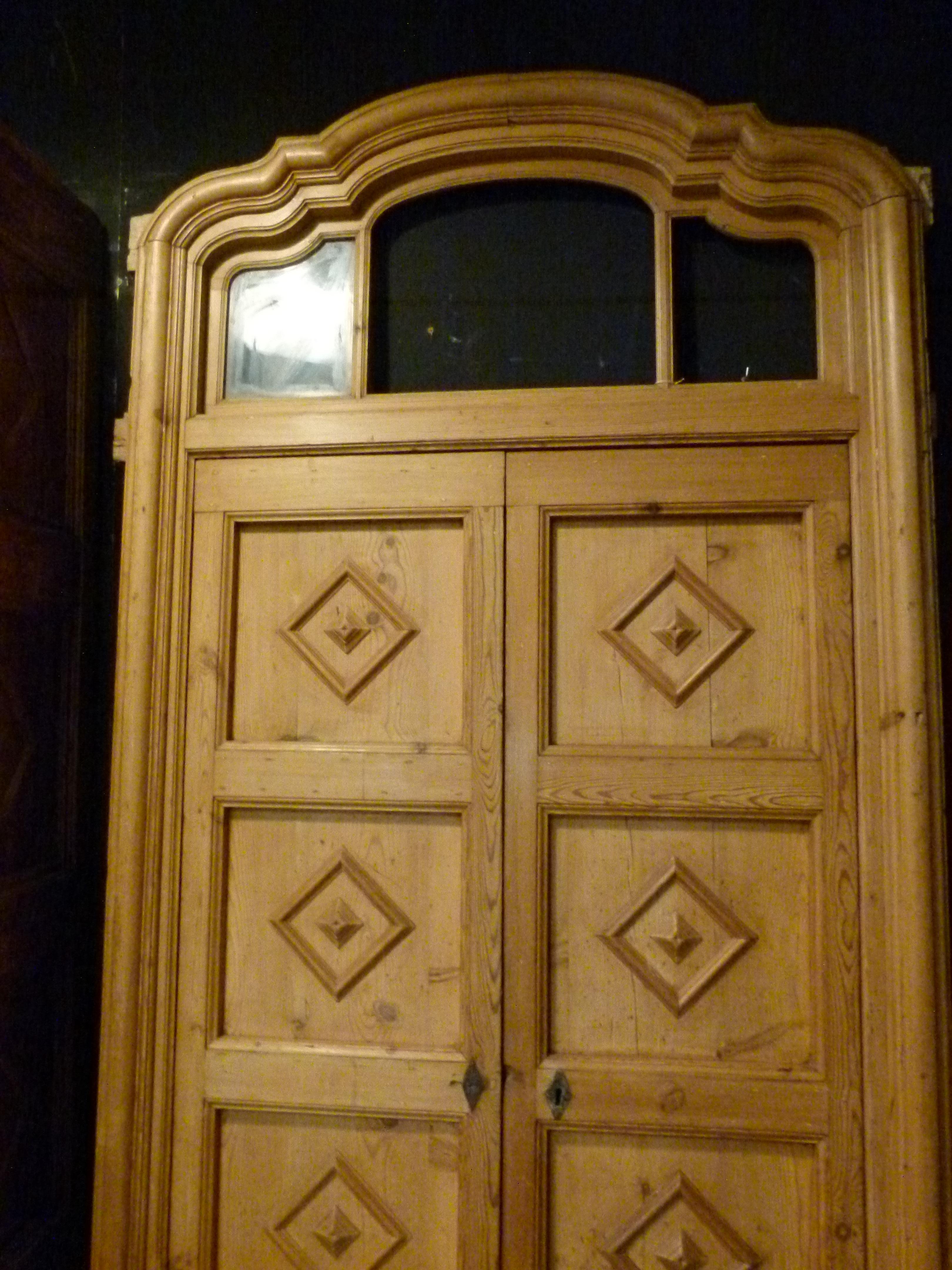 Hard wood front door from the 19th century in Spain. Nice carved decorations with three small glass windows on the top.