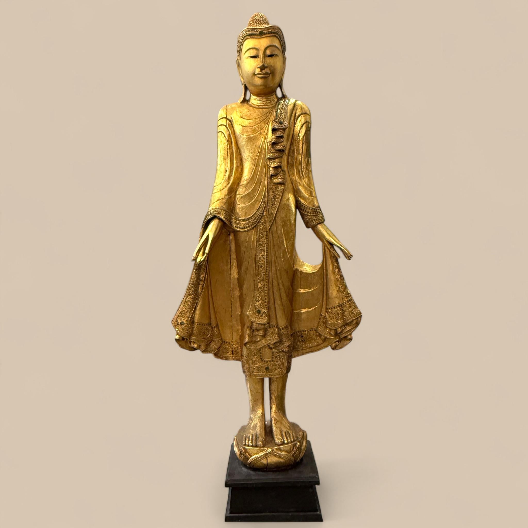 Ce bouddha debout birman du 20e siècle incarne à la fois la présence spirituelle et le raffinement de l'artisanat. 

Sculptée dans le bois et richement dorée, la figurine capture l'élégance de l'art birman avec des proportions gracieuses et des