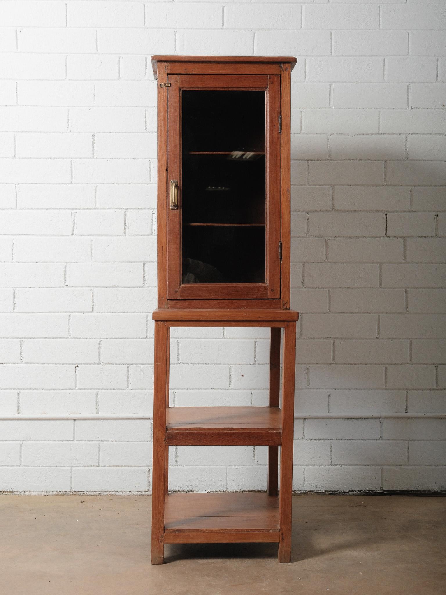 This charming wooden glass-front cabinet offers a warm, rustic presence and versatile function. Crafted from solid wood with a naturally aged finish, it features a single glass door opening to two interior shelves, ideal for displaying pottery,