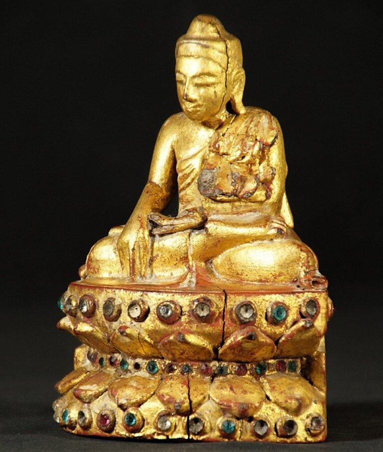 This antique wooden Buddha statue is a truly unique and special collectible piece. It is made of wood, standing 15 cm high, 10 cm wide and 7.5 cm deep, weighing 0.292 kgs. The intricate details on the statue are gilded with 24 krt gold, adding to