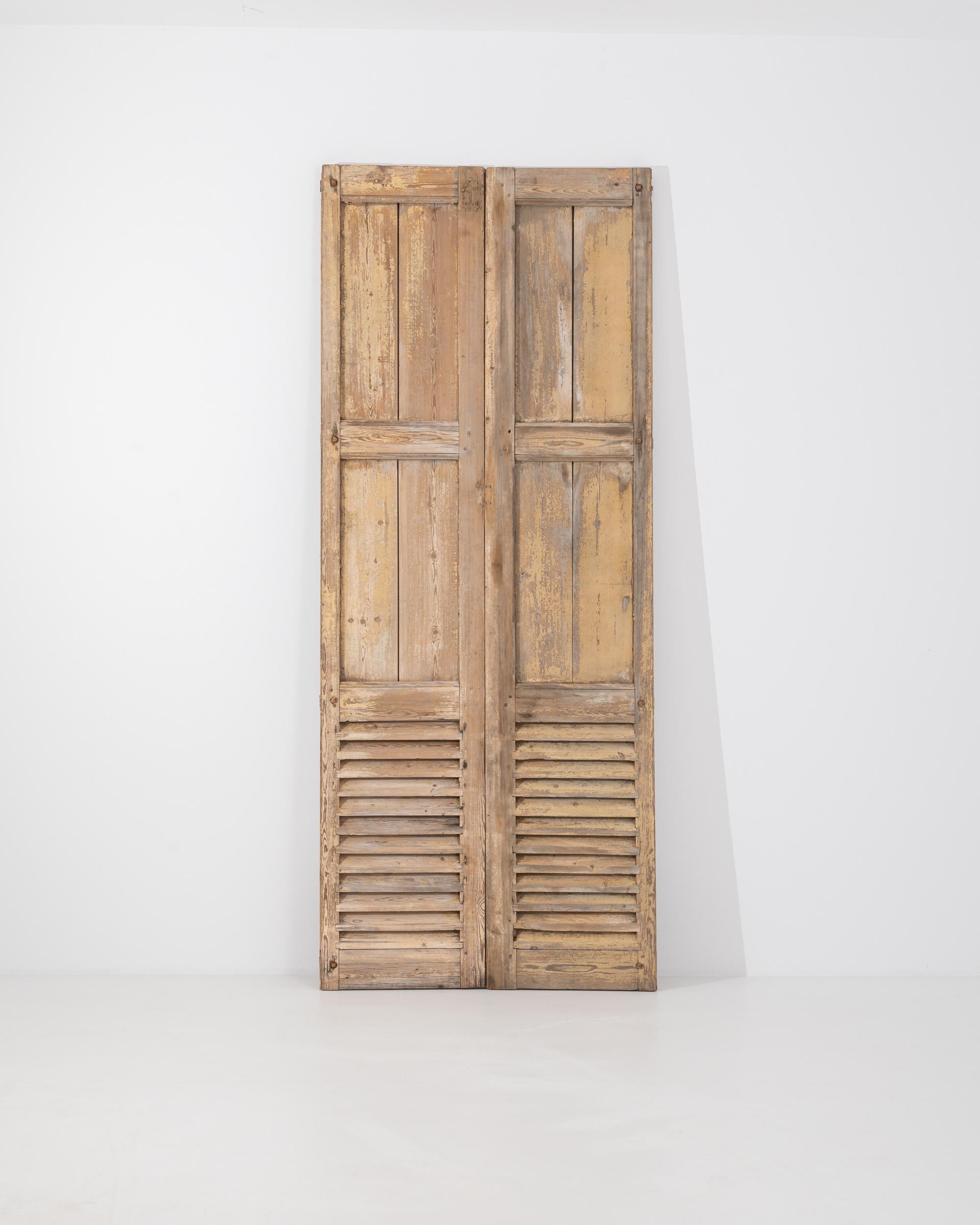 Ein Paar Holzfensterläden aus dem Frankreich des 19. Jahrhunderts. Mit ihrer beeindruckenden Höhe setzen diese Vintage-Fensterläden ein Zeichen der Anmut und strahlen gleichzeitig eine einladende Wärme aus. Eine lebendige und farbenfrohe Patina