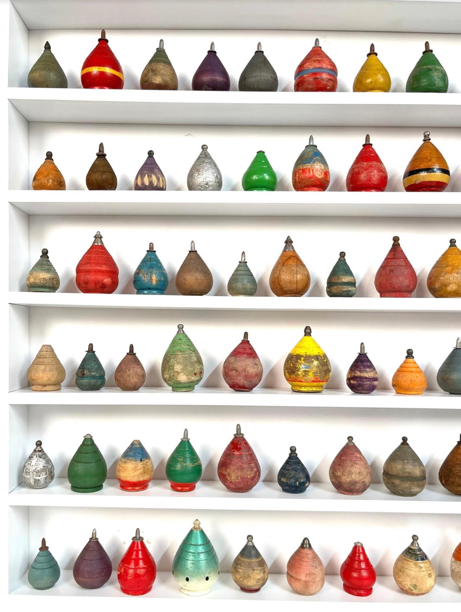 Large colorful collection of 104 antique spinning tops of various shapes and colors dating from 1880-1960. The tops are displayed in a custom-made cabinet grade white painted maple shadow box. The display case measures 32