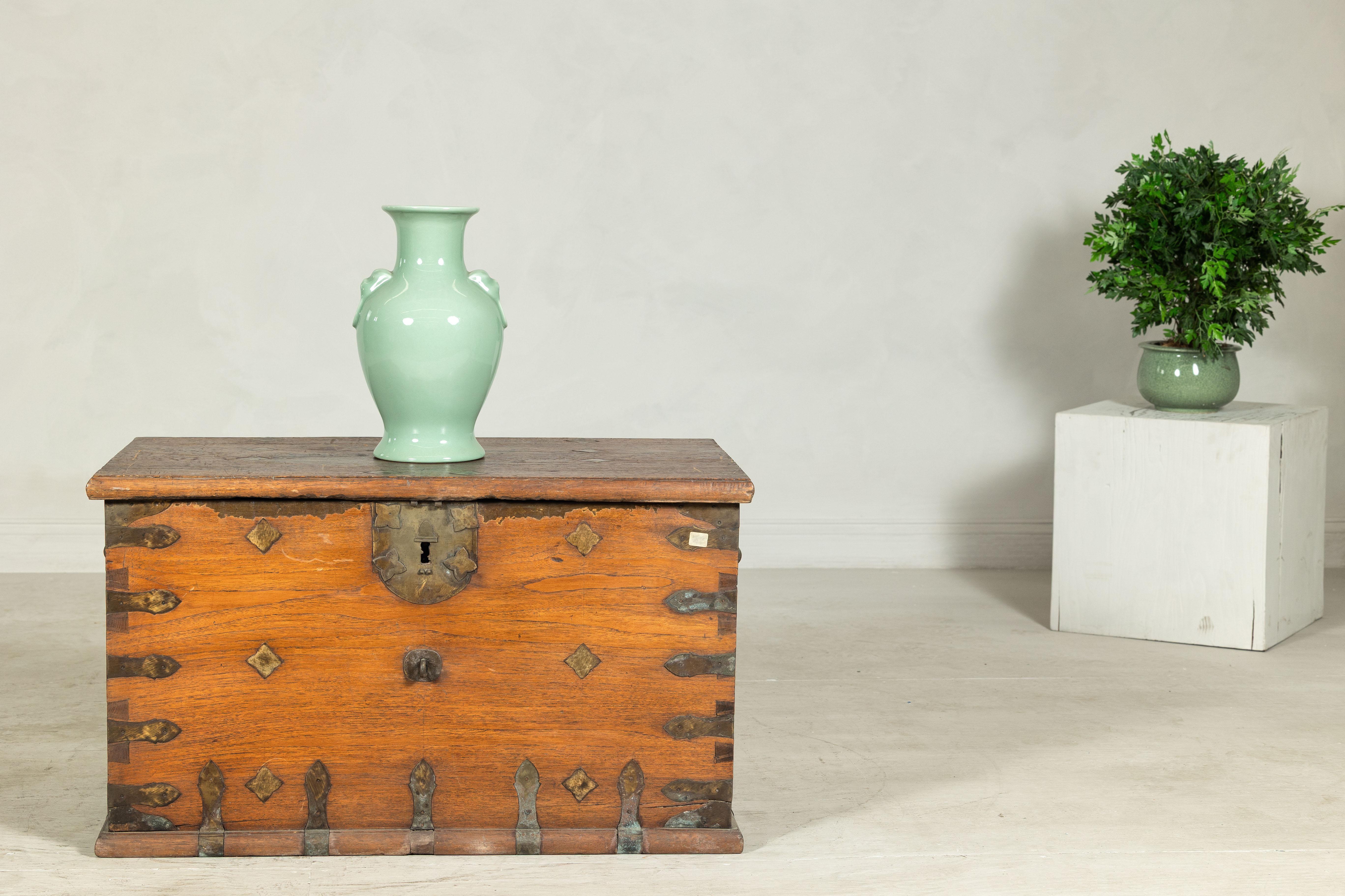 Questo antico baule in legno è caratterizzato da una caratteristica decorazione in metallo e da una robusta ferramenta in ferro, che unisce la funzionalità a un sorprendente ornamento fatto a mano. La forma rettangolare è rivestita da montature in