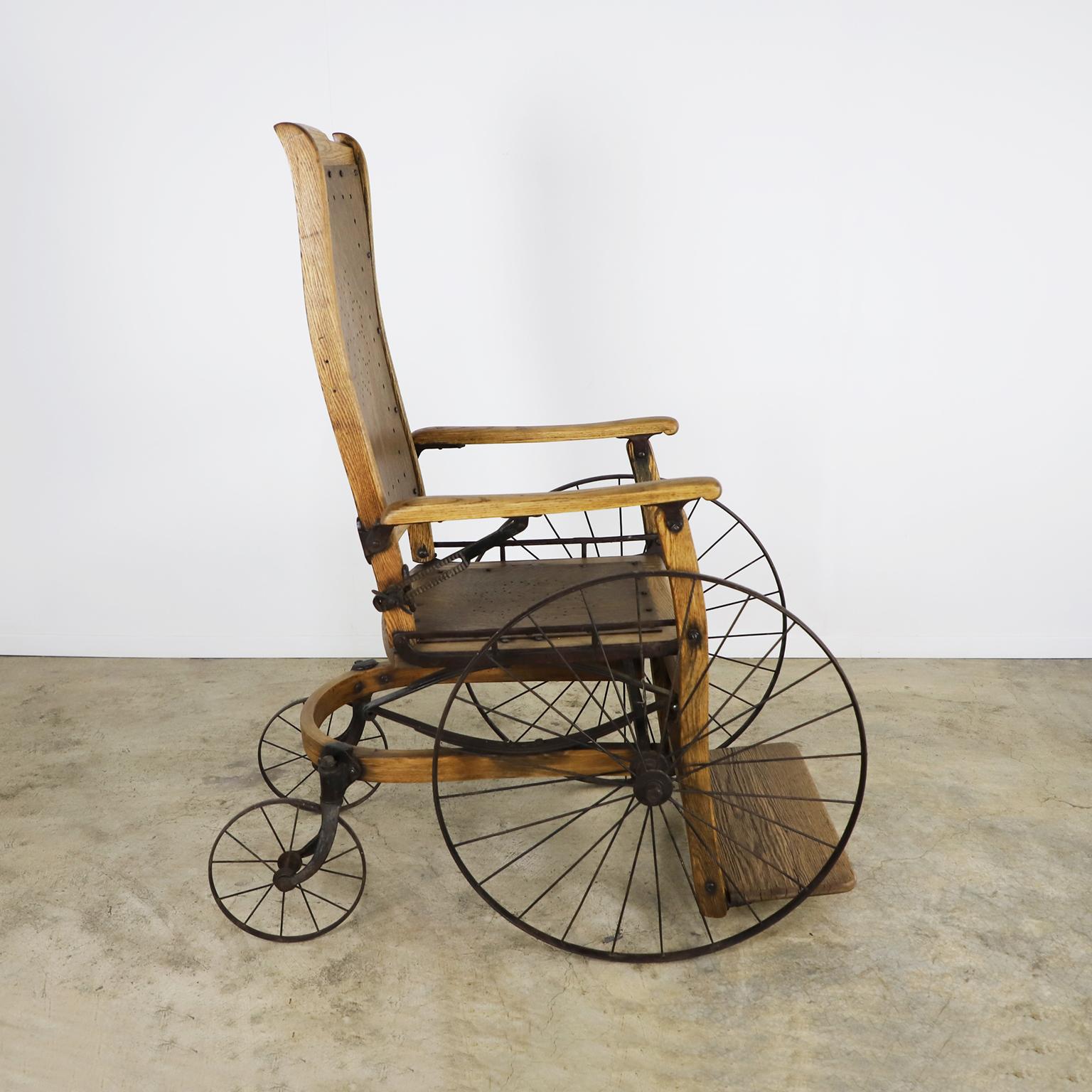 Circa 1900. Nous proposons ce rare Fauteuil roulant en bois. Fabriqué en bois et en fer, le fauteuil roulant présente une finition impeccable qui évoque le cœur de l'héritage industriel américain.
