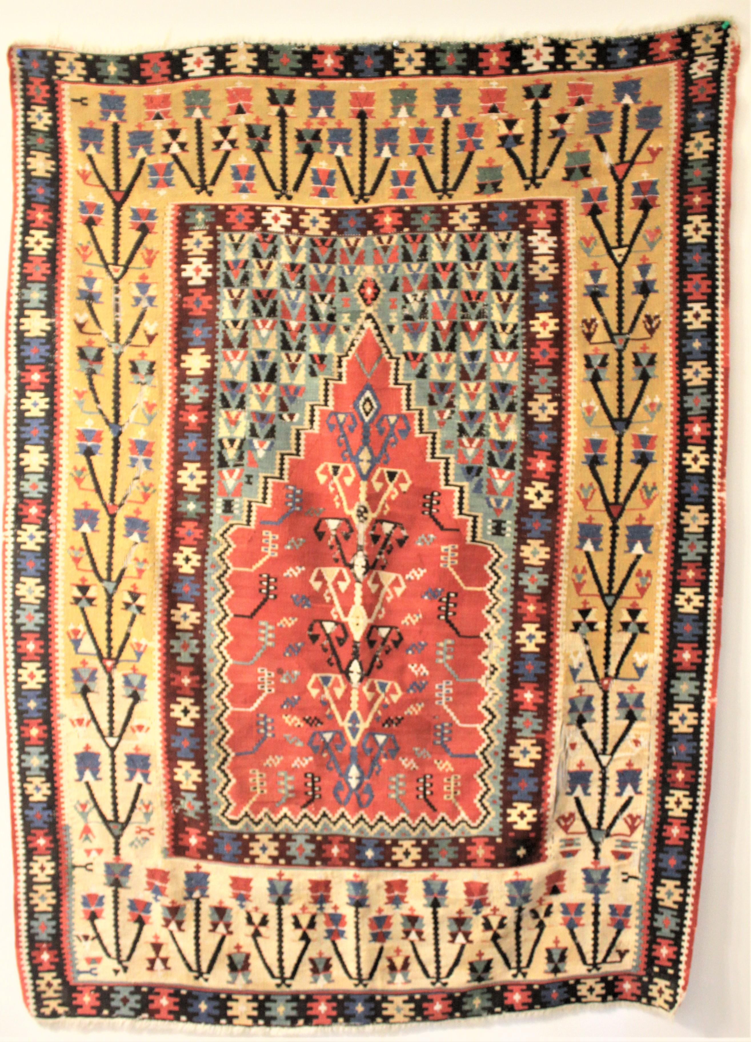 Dieser antike handgewebte Gebetsteppich wurde in der heutigen Türkei hergestellt und stammt aus der Zeit zwischen 1750 und 1780. Der Hintergrund dieses Teppichs ist in Pastelltönen gehalten, die das gedämpfte Rot des zentralen 