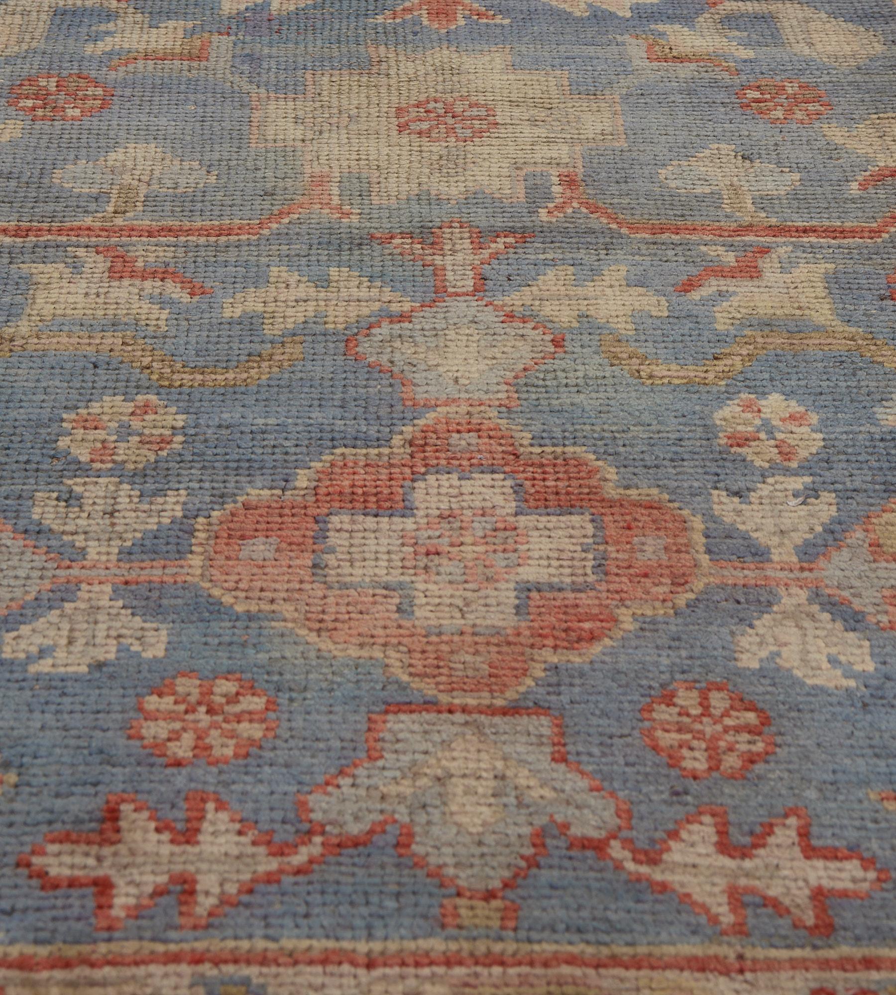 Dieser antike Oushak-Läufer hat ein schattiertes, himmelblaues Feld mit einer floralen und gezackten Blattranke, die eine Säule aus polychromen, spitz zulaufenden und gestuften Rauten mit je einem zentralen Blütenkopf innerhalb einer Tafel