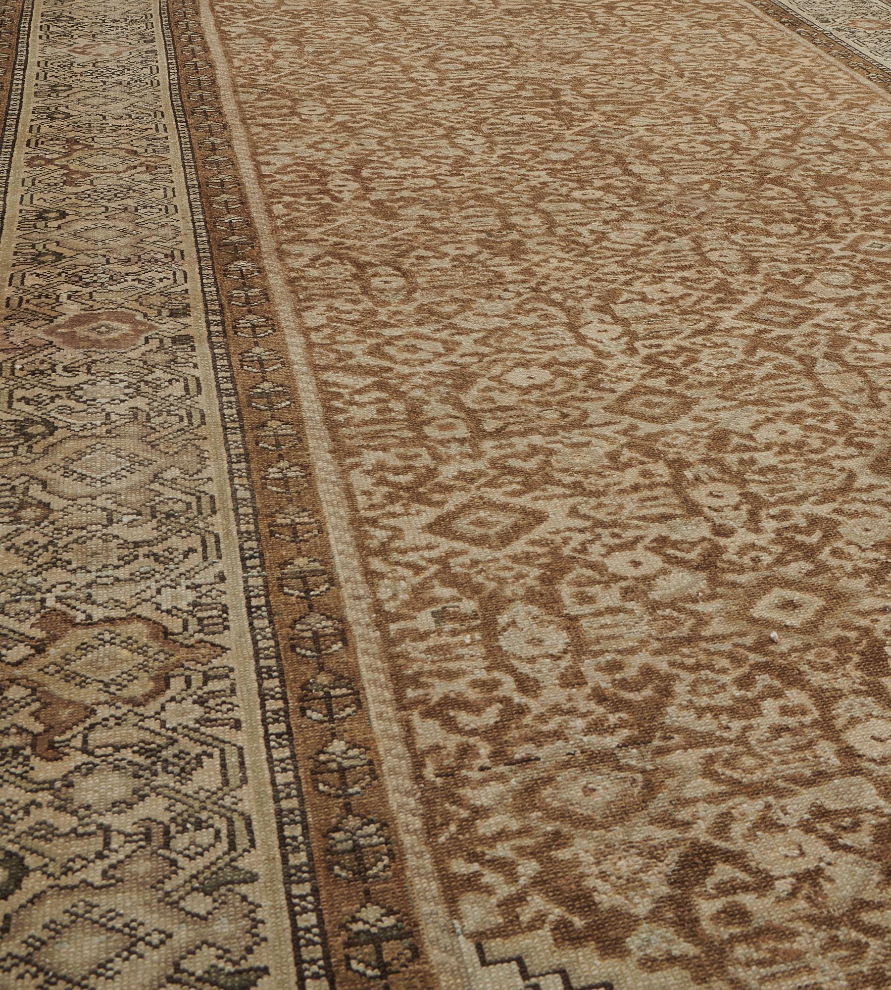 This antique Malayer rug has a fox-brown field with an overall dense herati-pattern, the buff-brown stepped spandrels with a angular lozenges and floral motifs, in a buff-brown angular turtle-palmette vine border between fox-brown linked floral vine