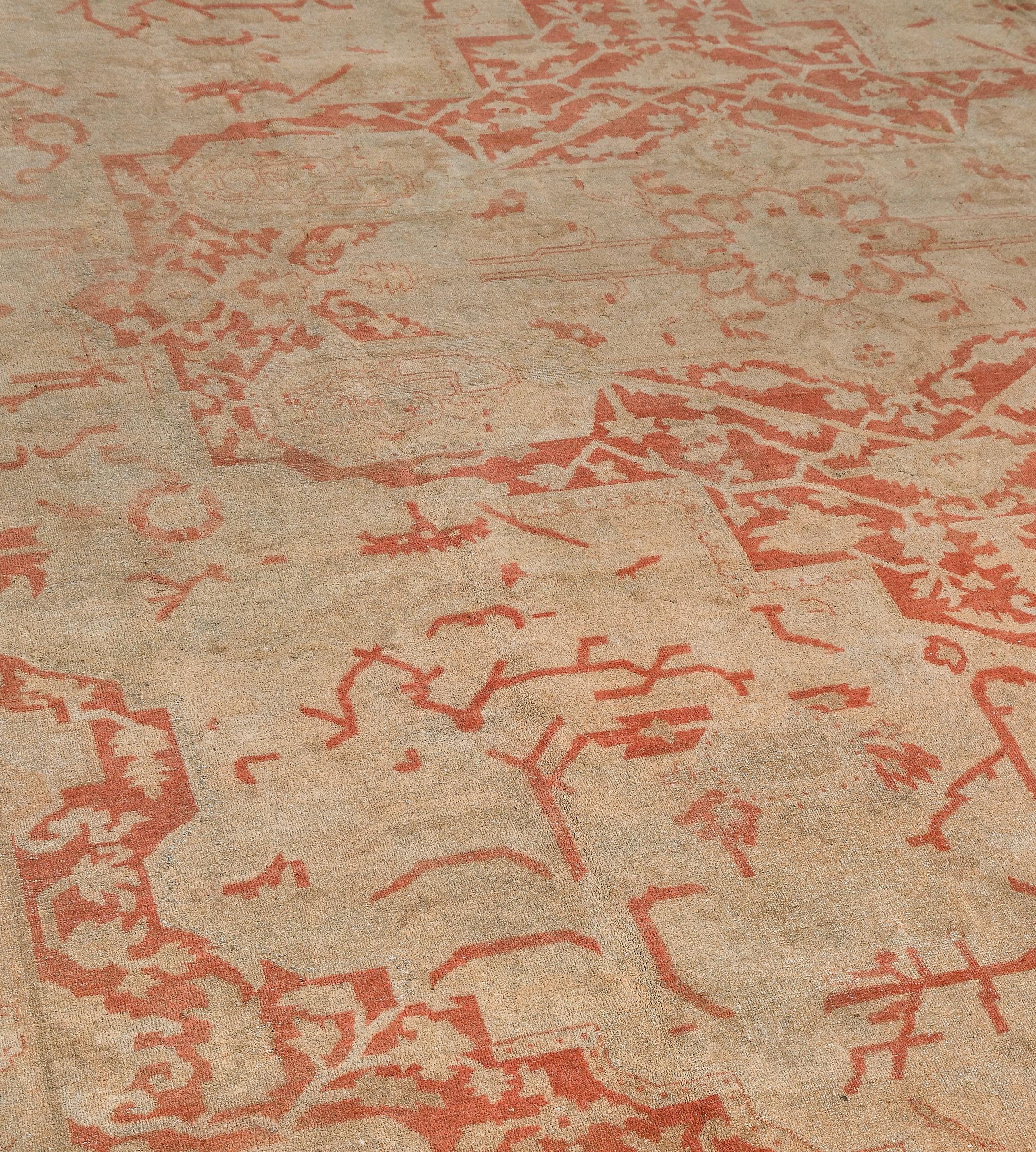 Cet ancien tapis indien d'Agra présente un champ ivoire nuancé avec des palmettes angulaires et une vigne florale autour d'un grand médaillon central cruciforme rouge terracotta doux émettant des palmettes audacieuses contenant une vigne florale