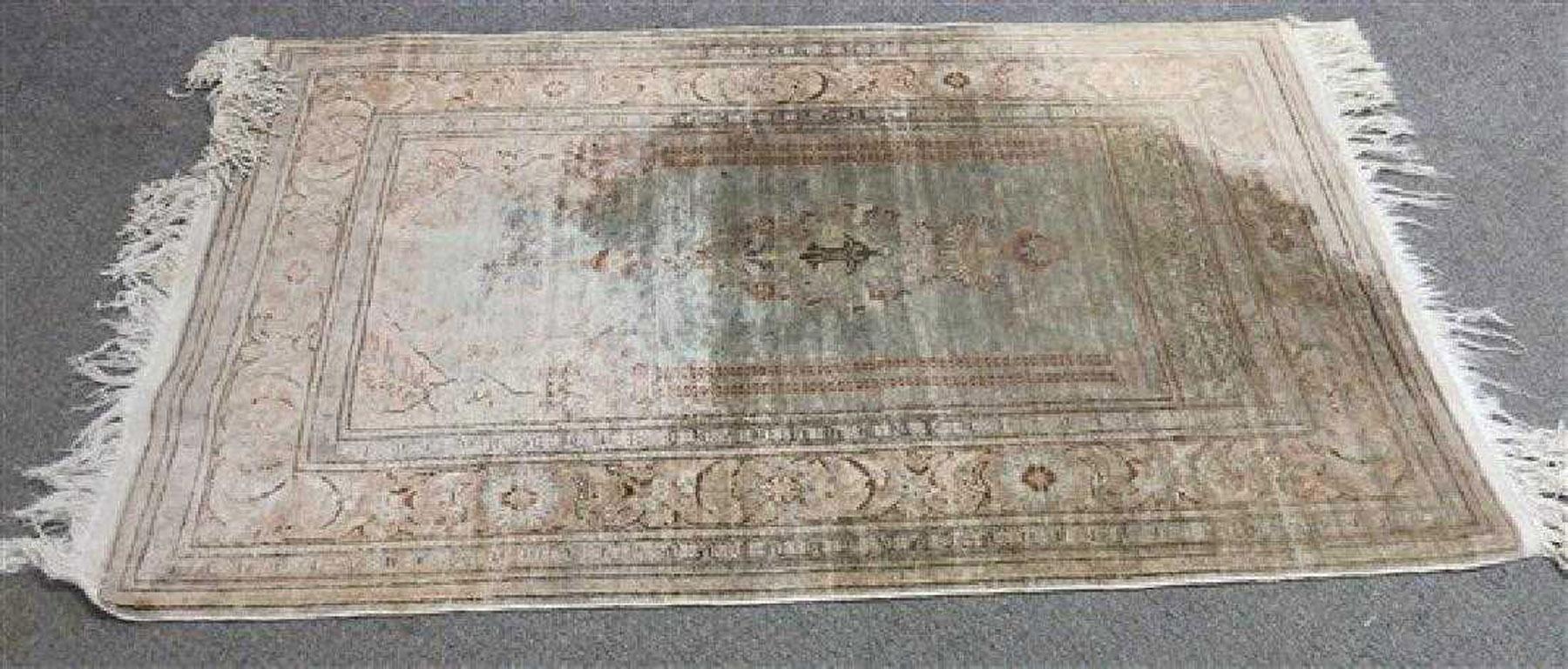 Ce tapis ancien en laine présente une arche à colonnes du Moyen-Orient au centre, avec une lanterne et d'autres motifs. La bordure est composée de feuilles et de fleurs stylisées. Les couleurs prédominantes sont le bleu, le vert et le brun.
Frange