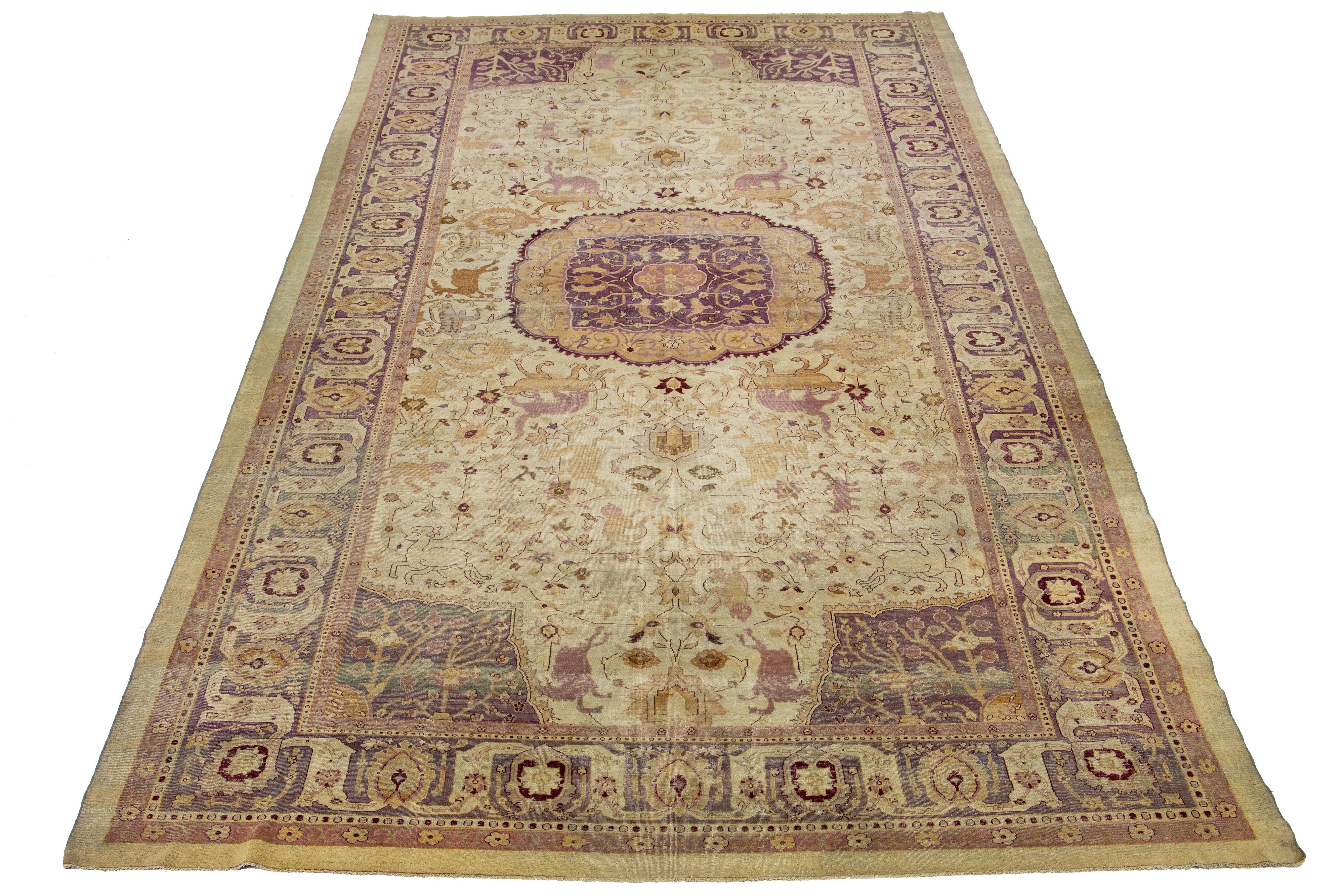 Diese wunderschön handgefertigte  Der Wollteppich Agra zeigt ein klassisches Blumenmuster. Der Kontrast, der durch den beigen Hintergrund entsteht, hebt das florale Medaillonmuster in Violett- und Brauntönen hervor.

Dieser Teppich misst  10'5