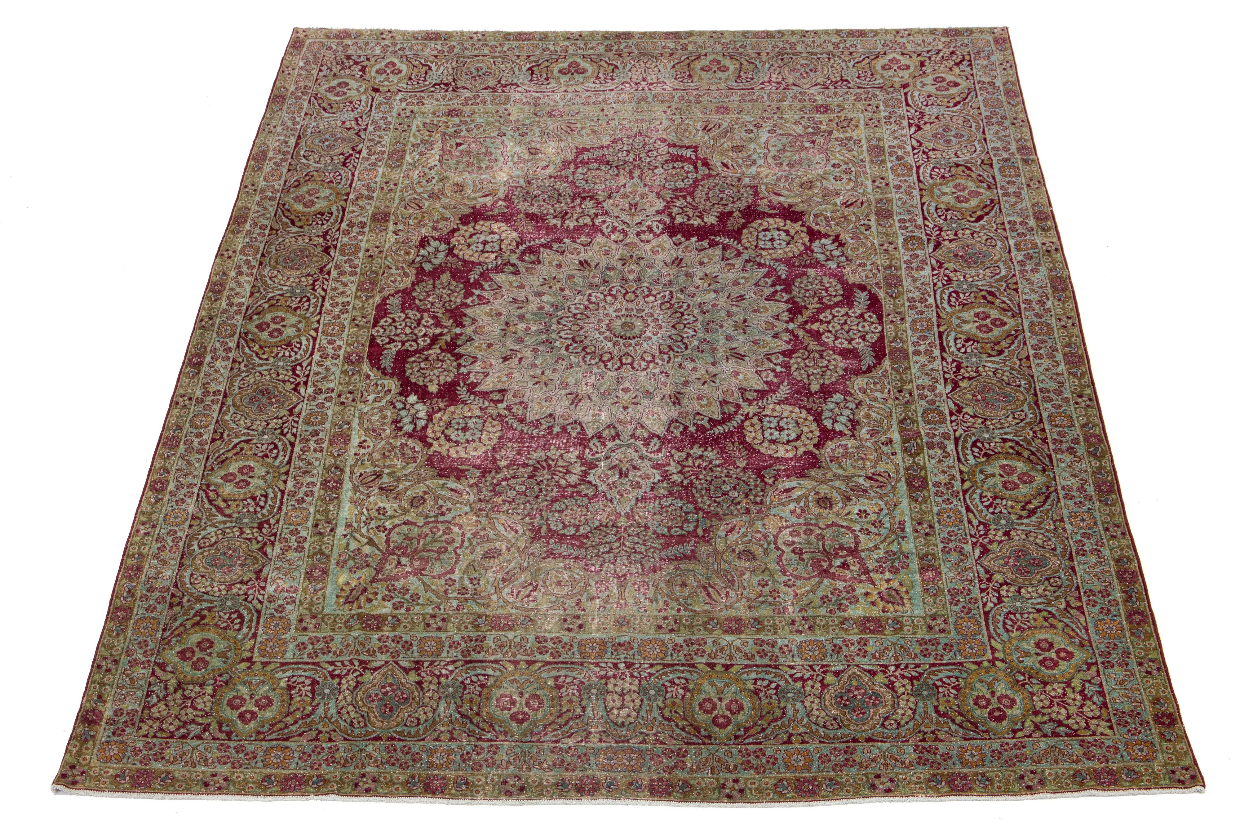This Persian Kerman wool rug from the early 1900s showcases a meticulously crafted allover floral design in blue and goldenrod. This antique rug features a raspberry red field.

This rug measures 9'8