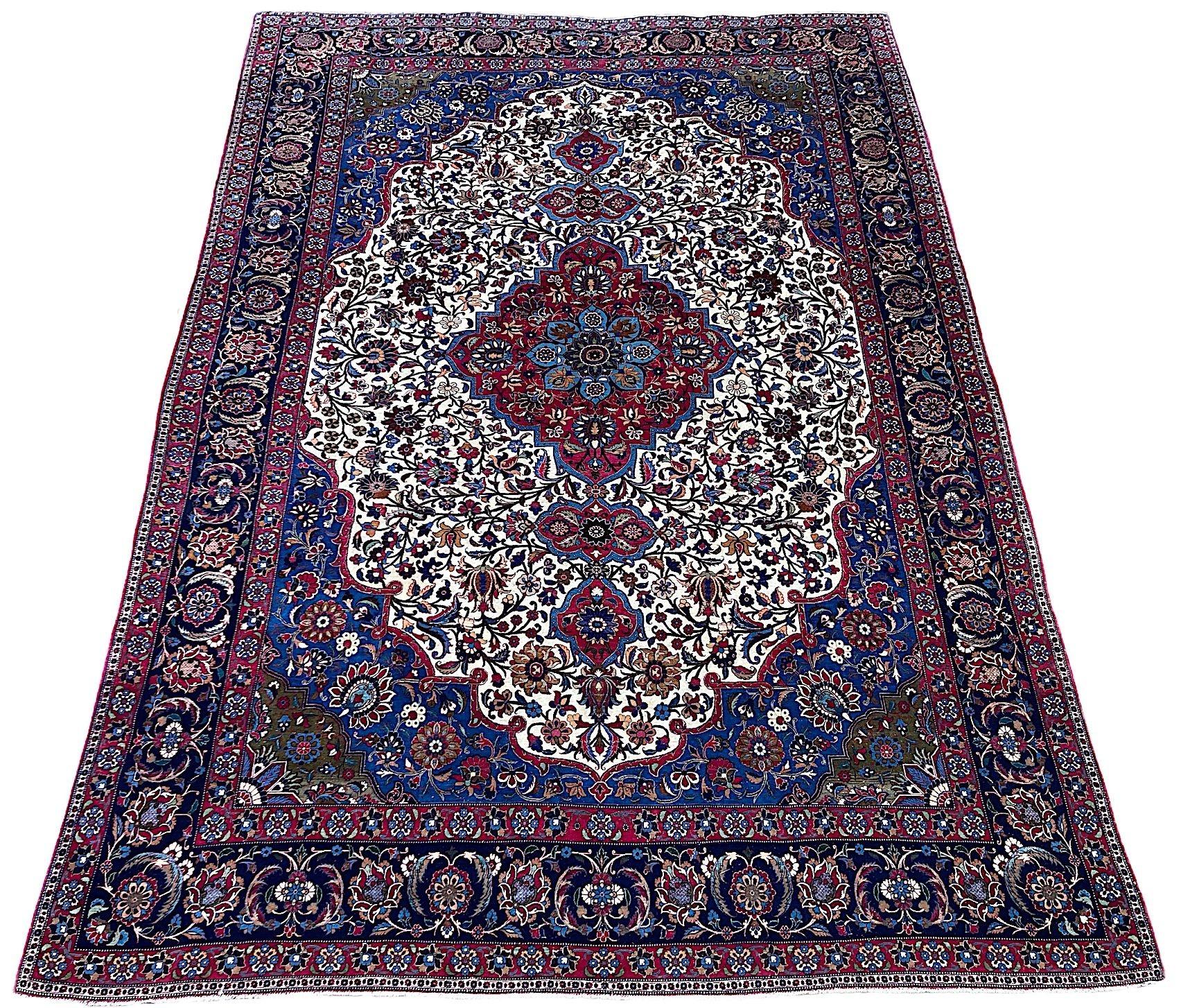Ein hervorragender Isfahan-Teppich aus Wolle und Seide, handgewebt um 1920. Das Design zeigt ein einzelnes Medaillon auf einem elfenbeinfarbenen Feld aus Blumen und Ranken, umgeben von einer indigoblauen Bordüre mit großen Blütenköpfen. Fein gewebt