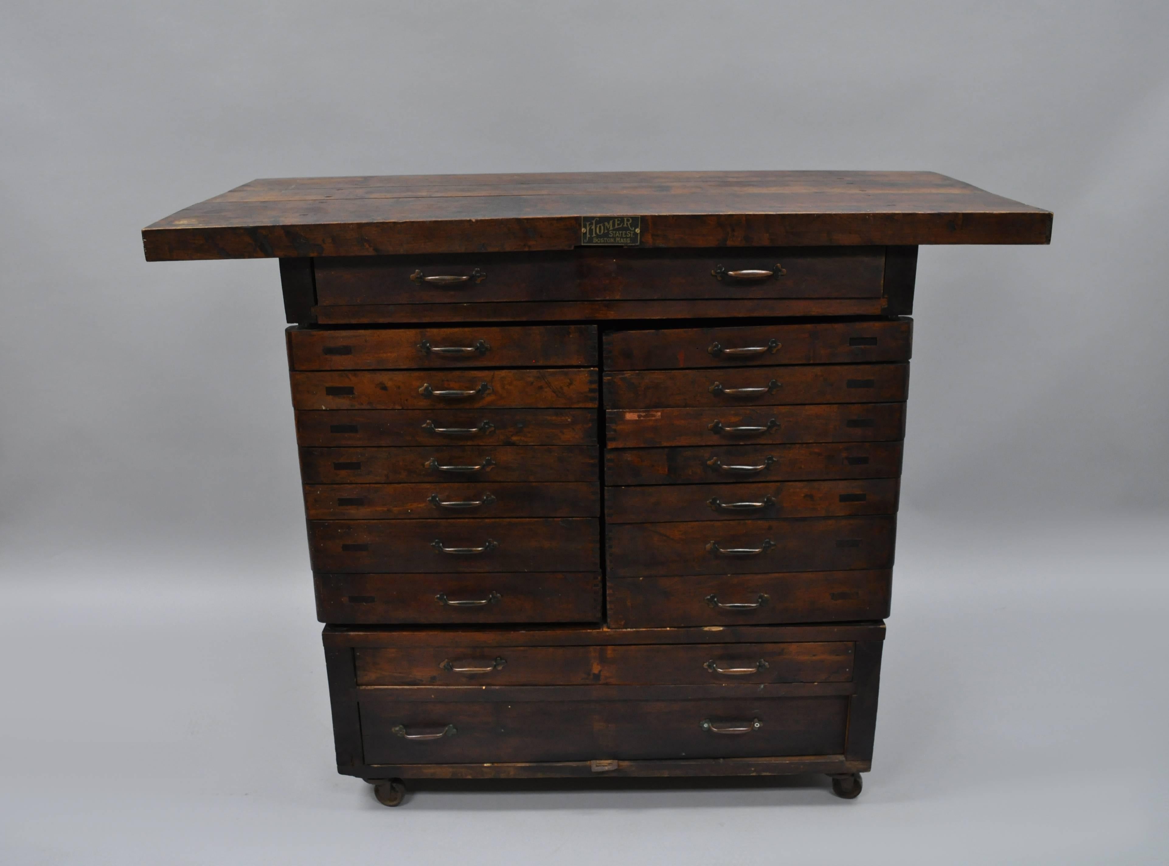 Antique work cabinet by Homer State St. Boston, MA, circa Early 1900s. Item features solid wood construction, 14 swing hinged staggered drawers, three flat drawers, metal rolling casters, beautiful patina, plenty of storage, original metal tag, very