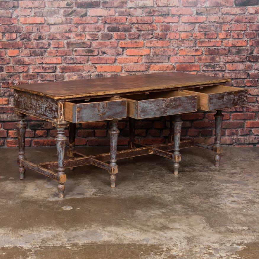 Old layers of distressed blue/gray and deep brown/rust colored paint create an attractive mix in this unique work table. The paint has been worn down to the natural pine in many areas, creating an 