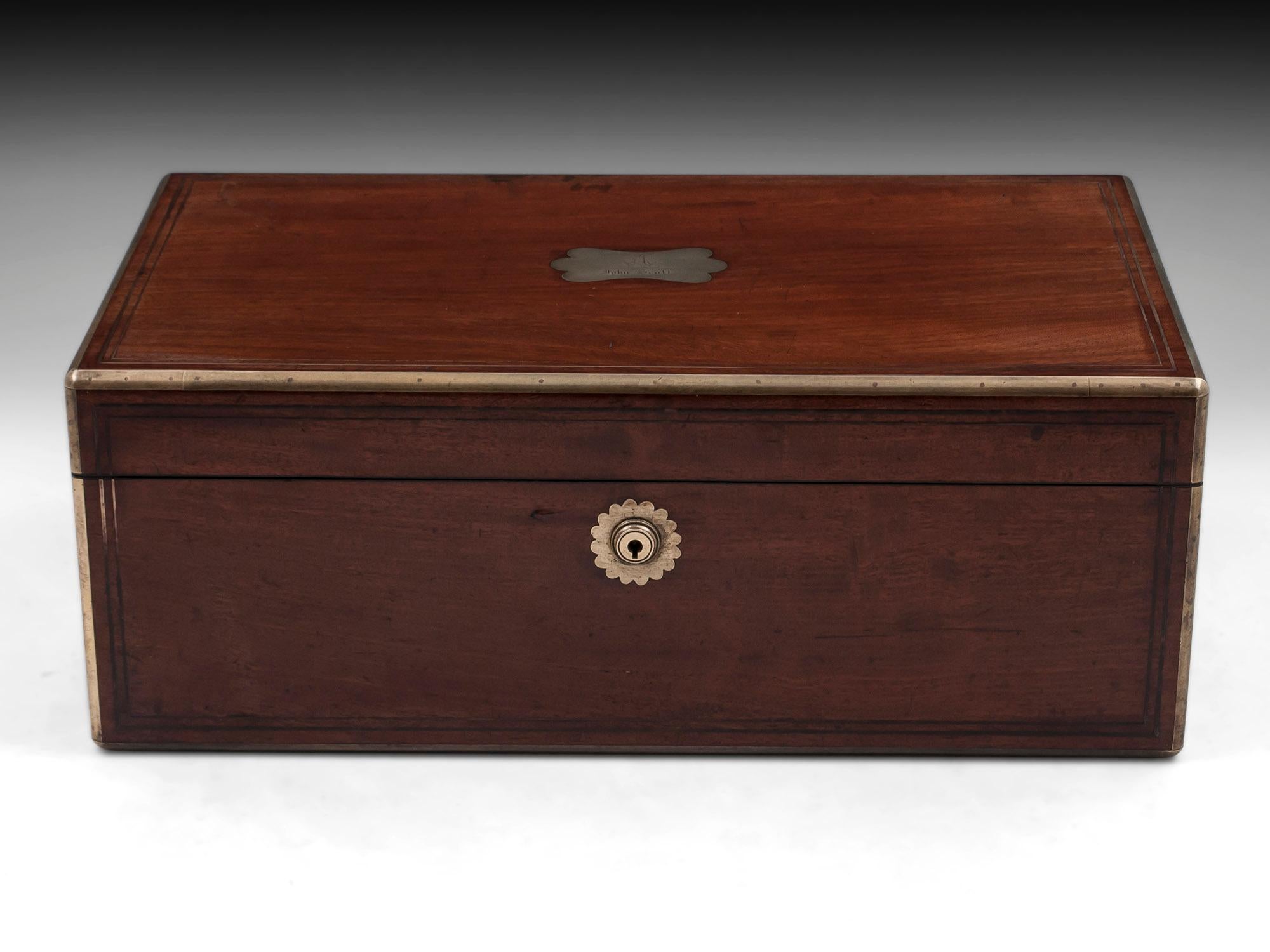 Antique brass bound mahogany writing box with double brass stringing, flush carry handles and shaped initial plate with an engraved coat of arms and the name John Scott.
The interior features a burgundy leather writing surface with beautiful gold